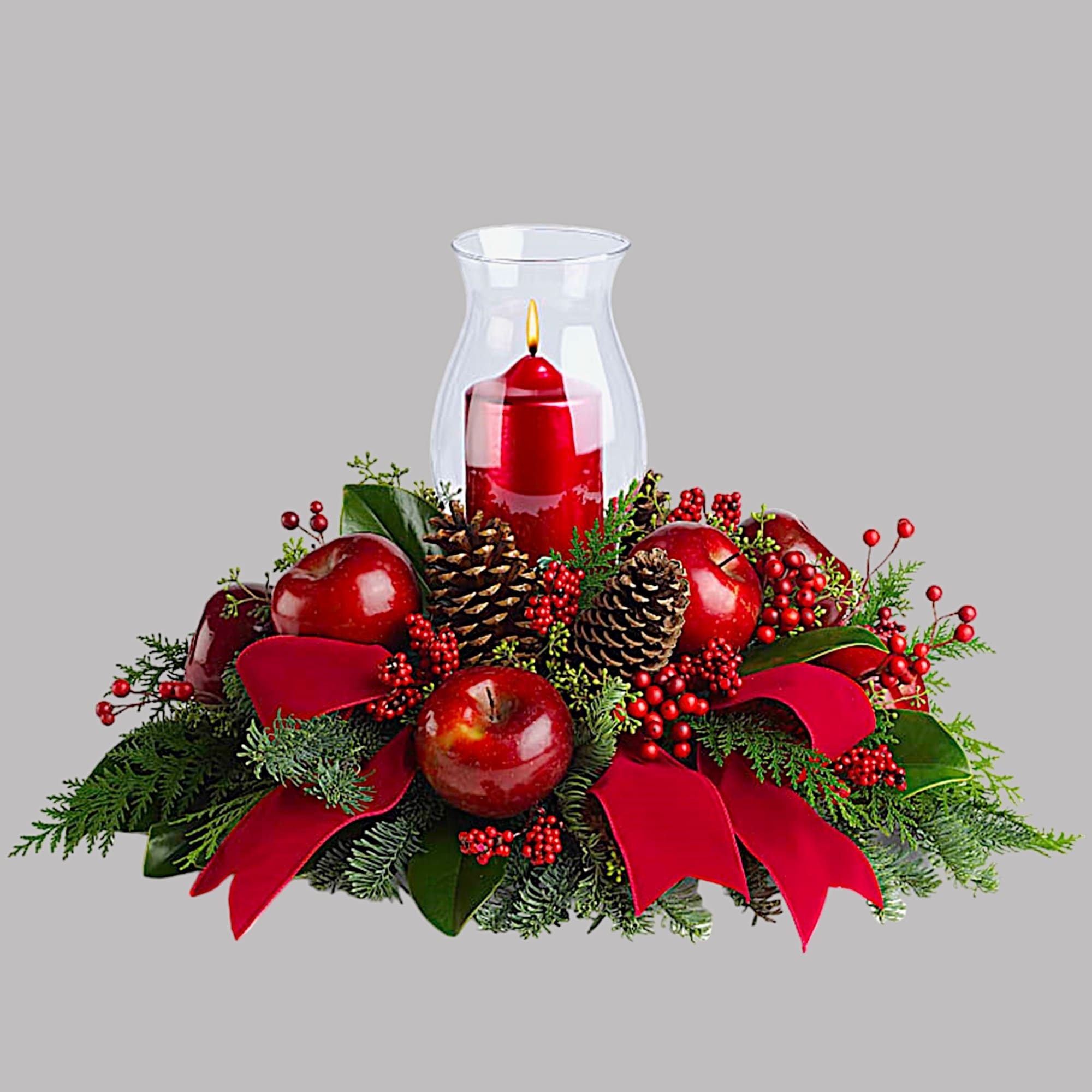 Red candle in a glass hurricane surrounded by apples, pinecones, and ribbon, photo 4 of 4
