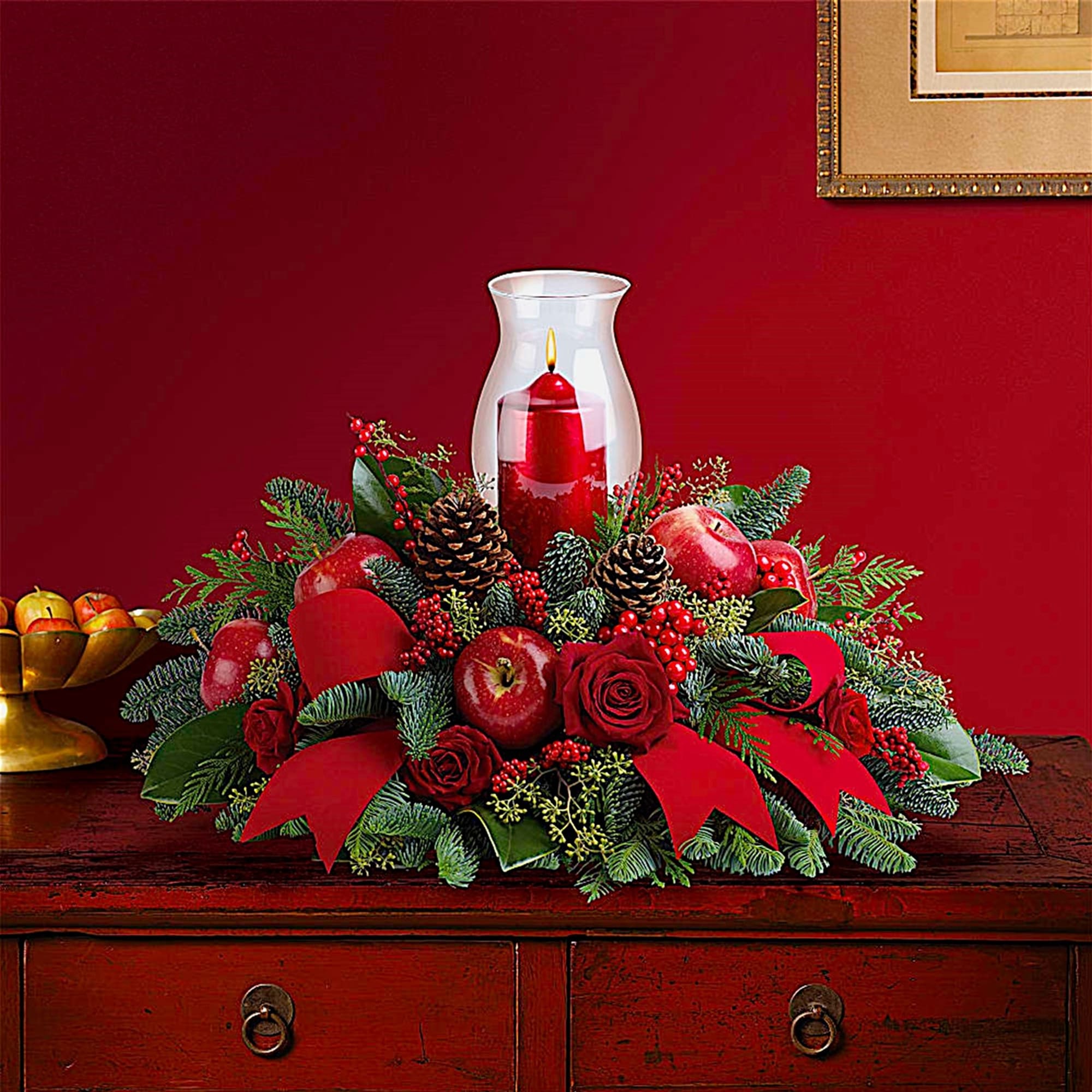 Red candle centerpiece with apples, pinecones, and roses
