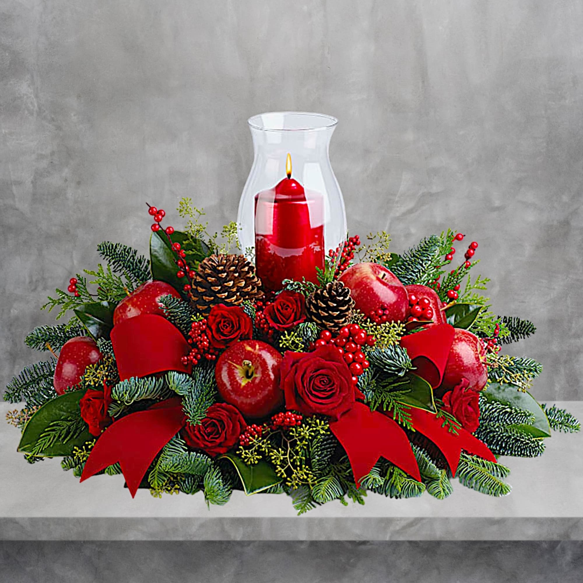 Red rose centerpiece with apples and a candle in a glass hurricane