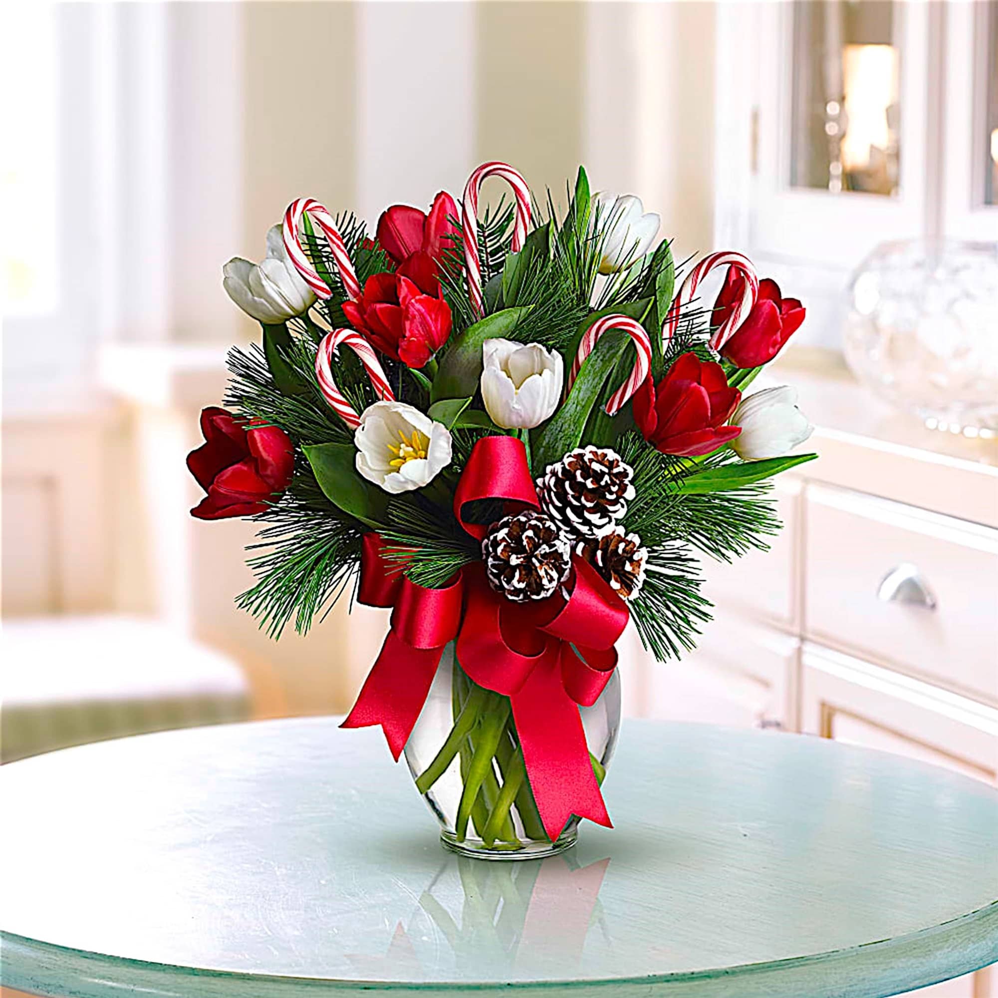 Holiday bouquet of red and white tulips with candy canes in a glass vase