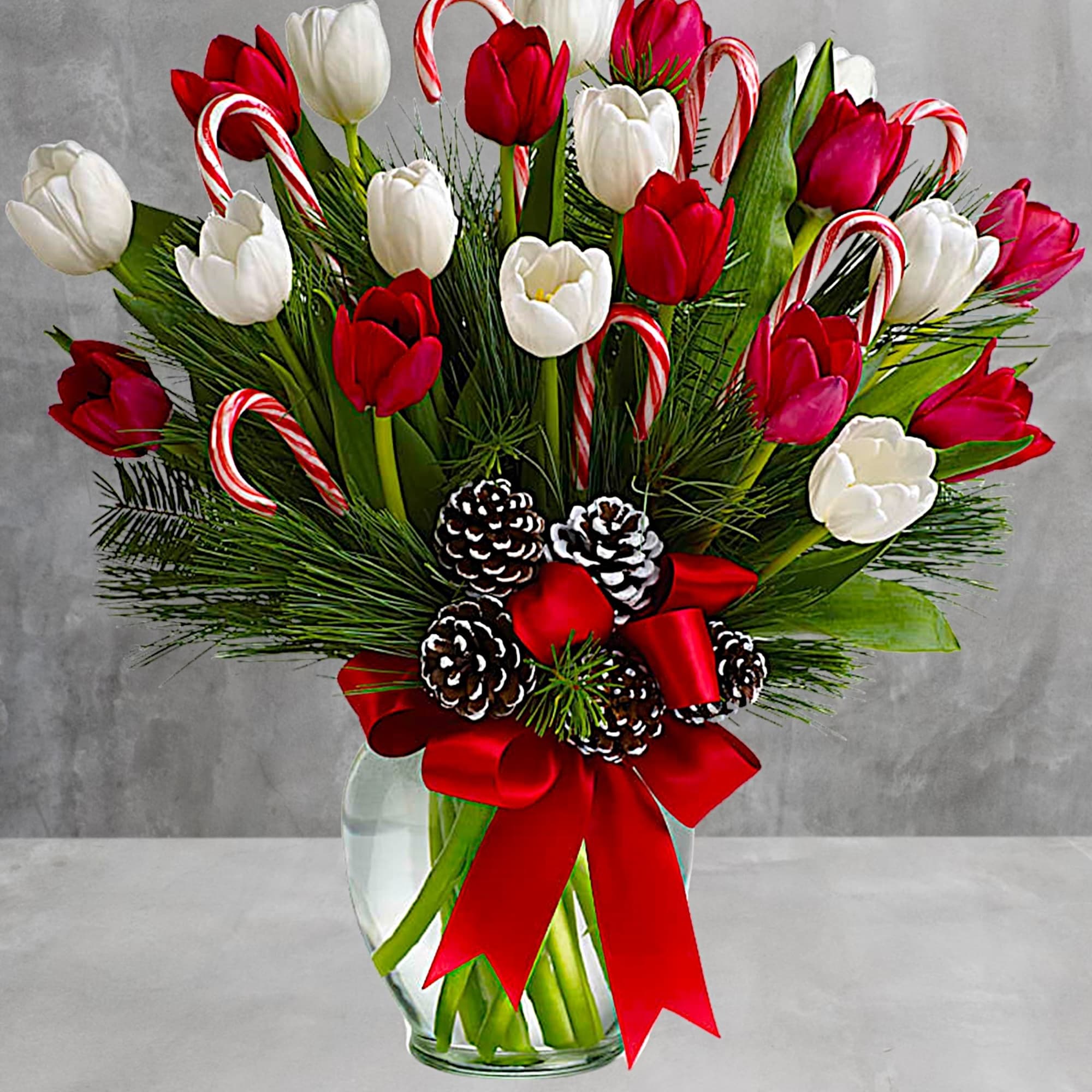 Red and white tulips in a glass vase with candy canes and pinecones, photo 2 of 4