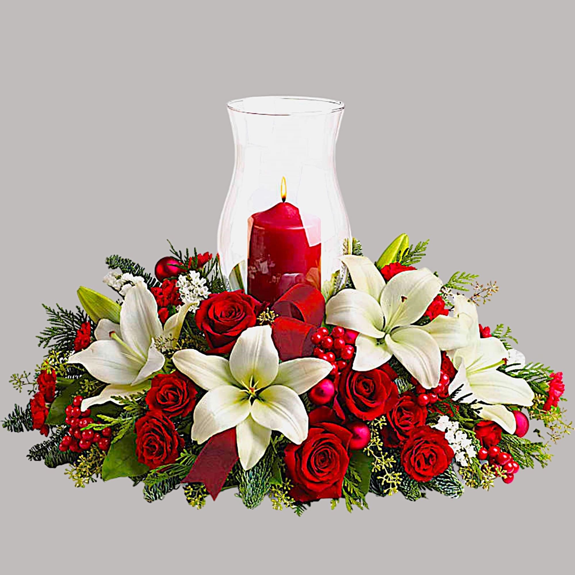 Red roses and white lilies around a red candle in a glass hurricane vase