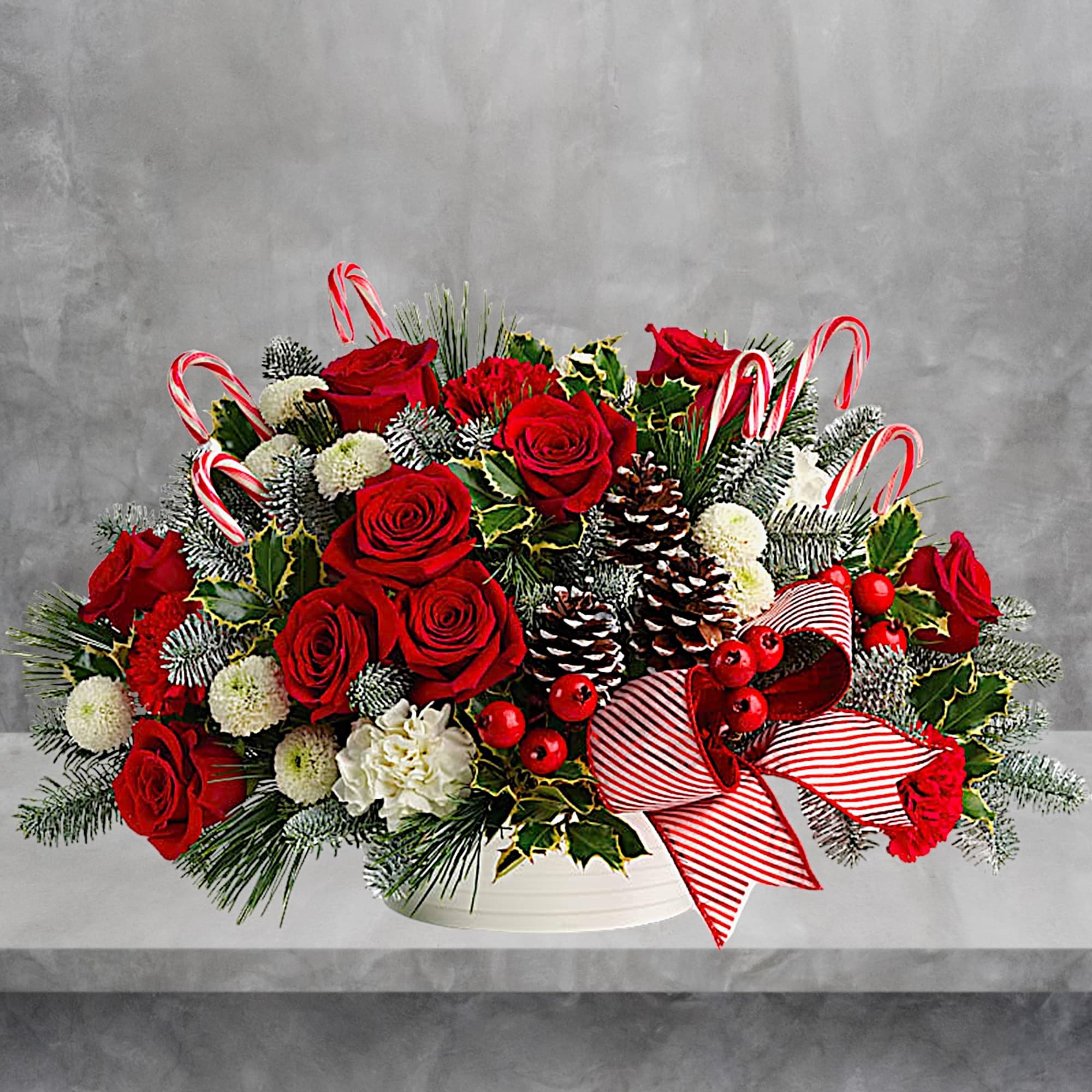 Red roses and white flowers in a white basket with candy canes and a striped bow