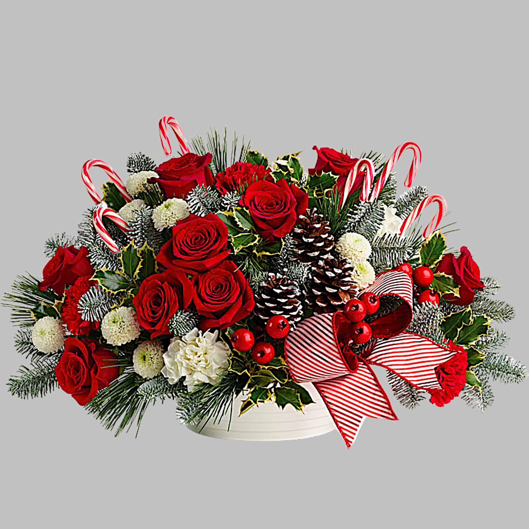Christmas arrangement of red roses, pinecones, and candy canes in a white bowl