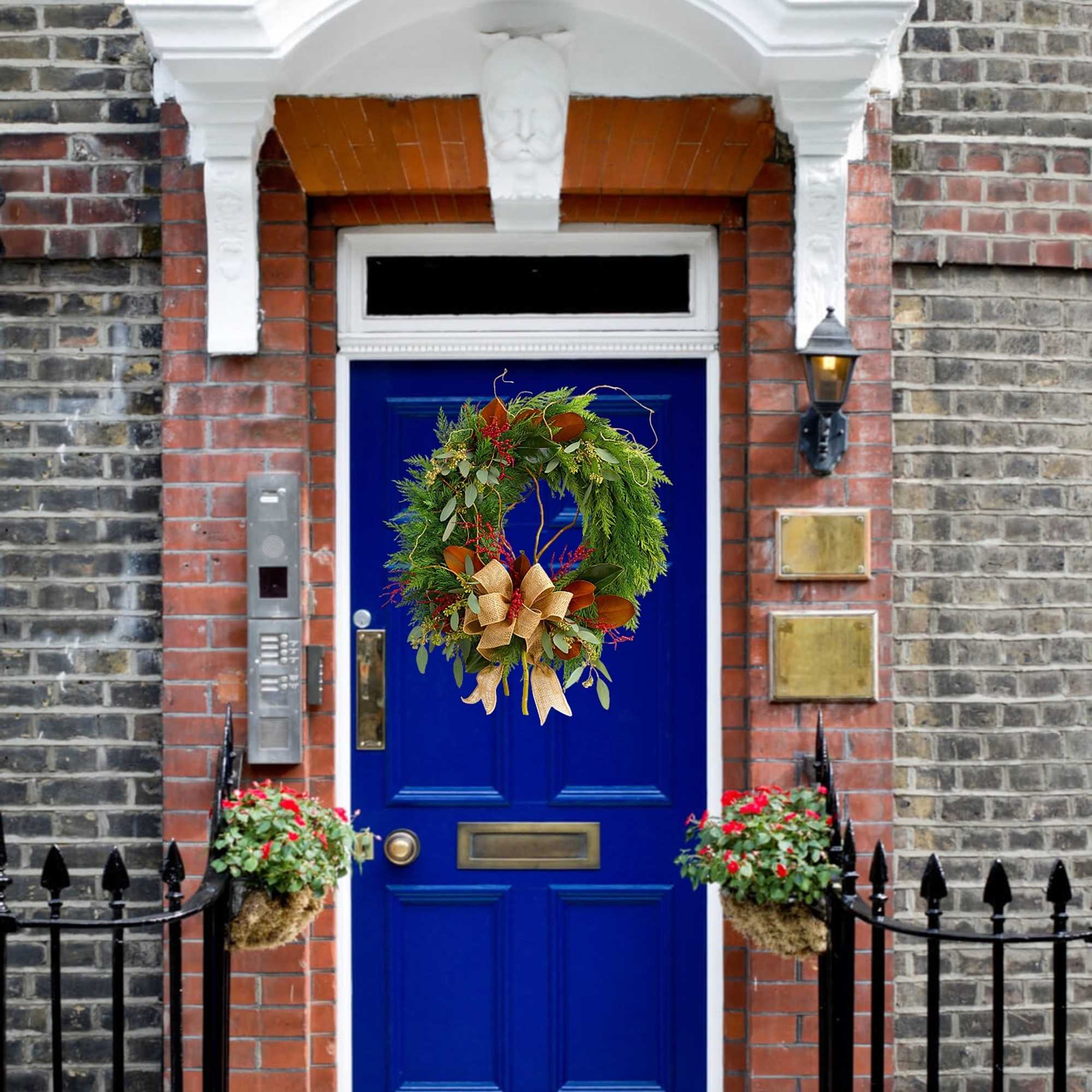 Front door with a green holiday wreath and two small flower baskets