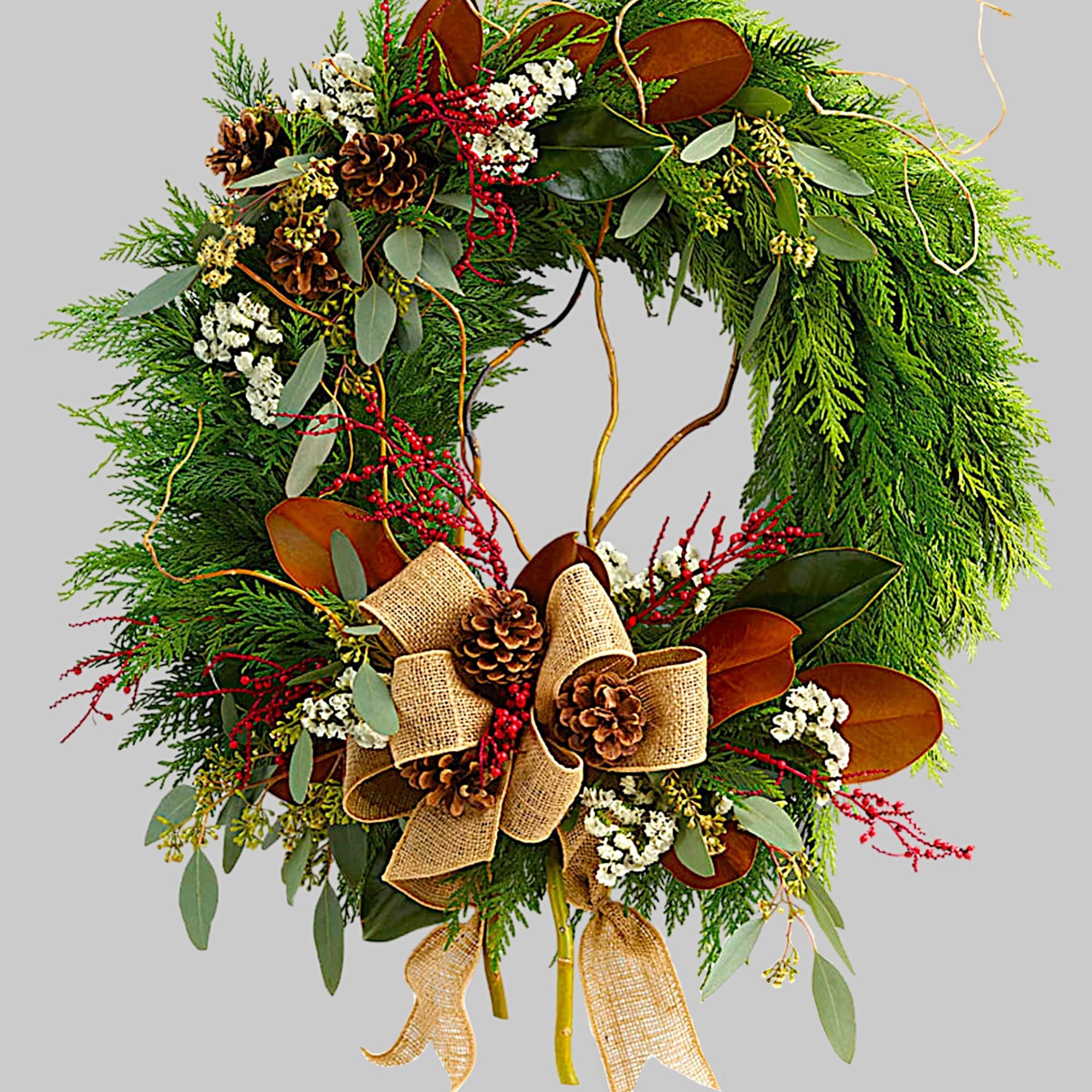 Holiday wreath with pine, berries, pinecones, and burlap ribbon