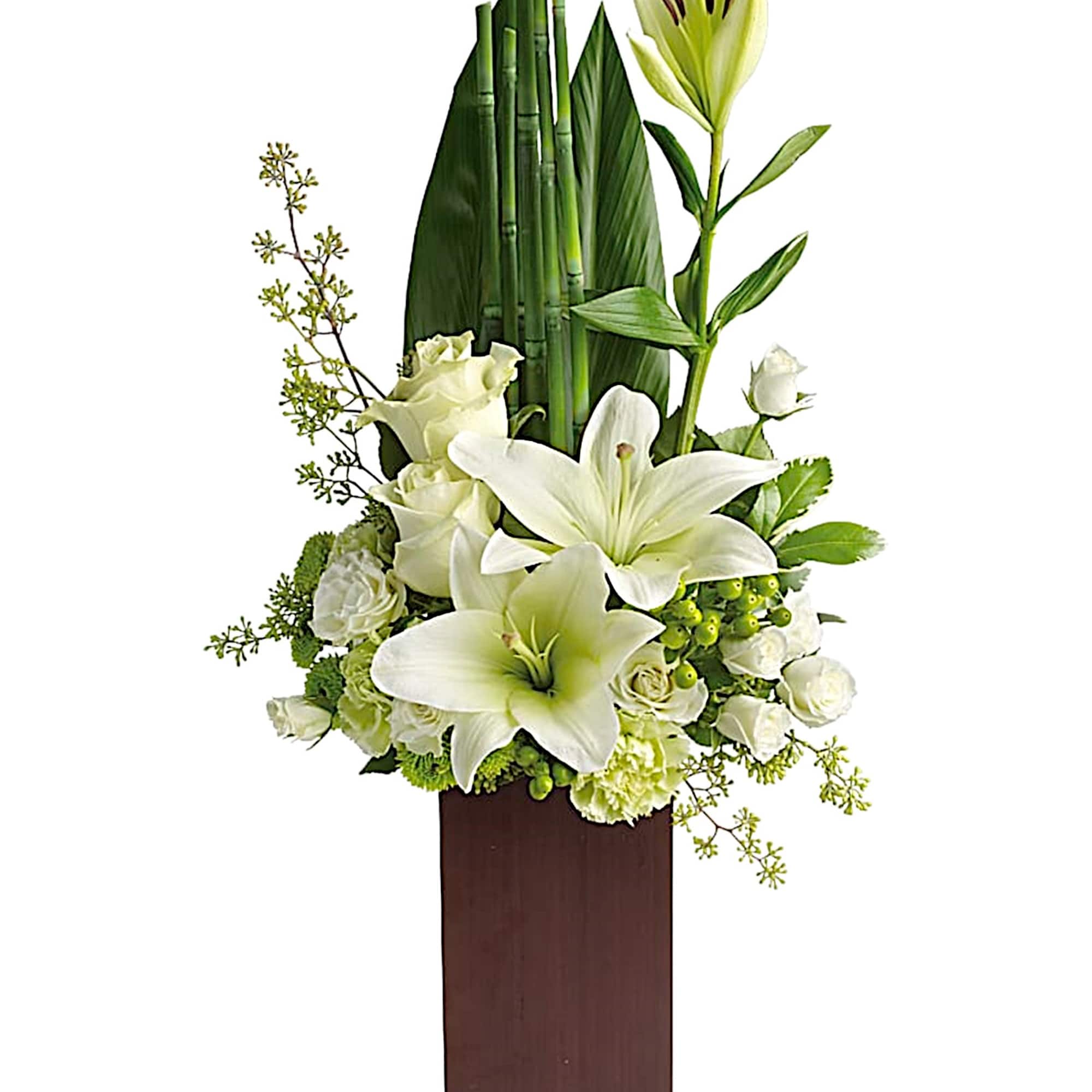 White lilies and roses in a tall wooden vase arrangement