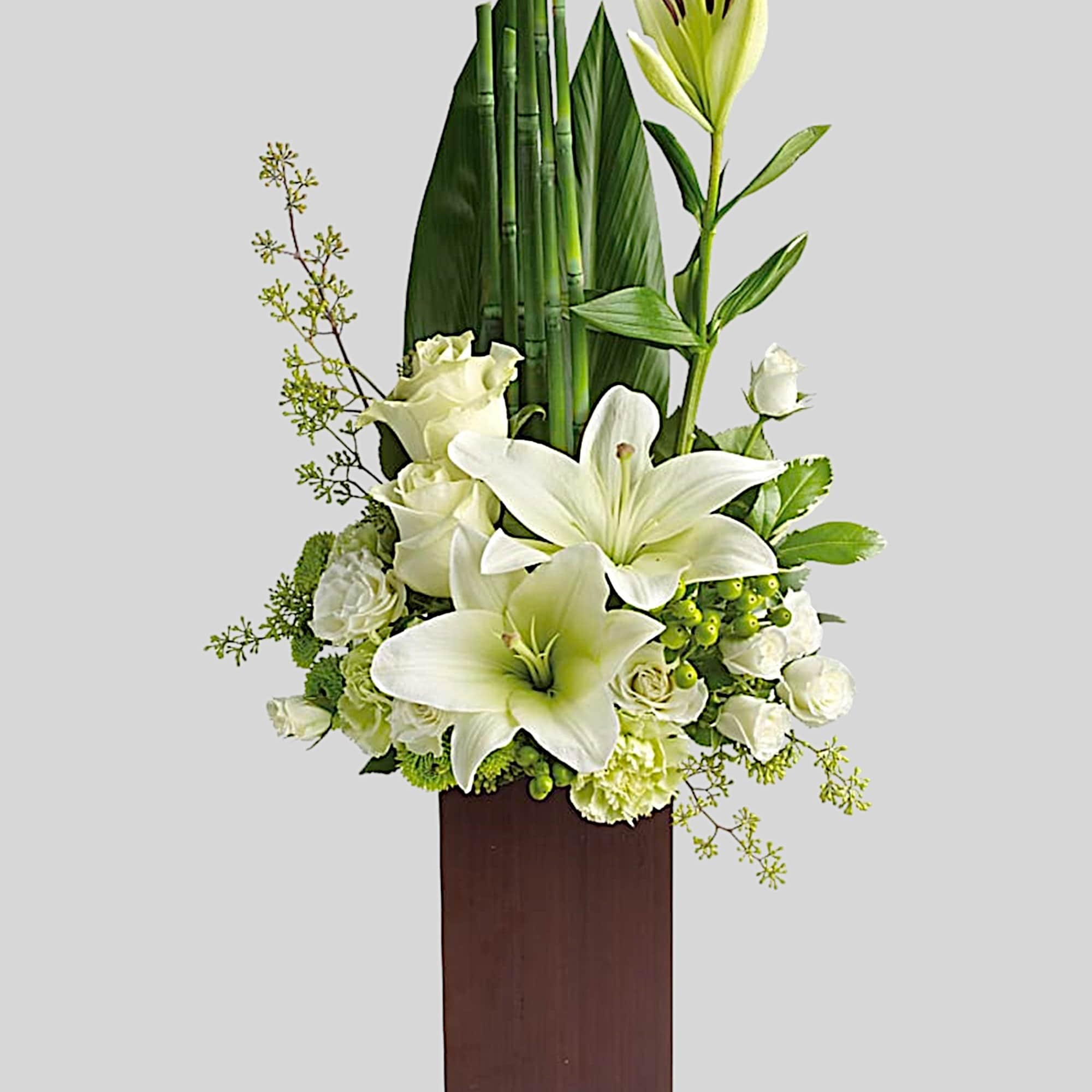 White lilies and roses arranged in a tall wooden vase