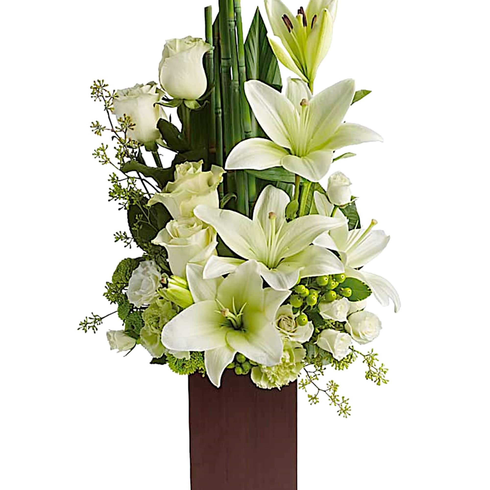 White lilies and roses arranged in a tall wooden vase
