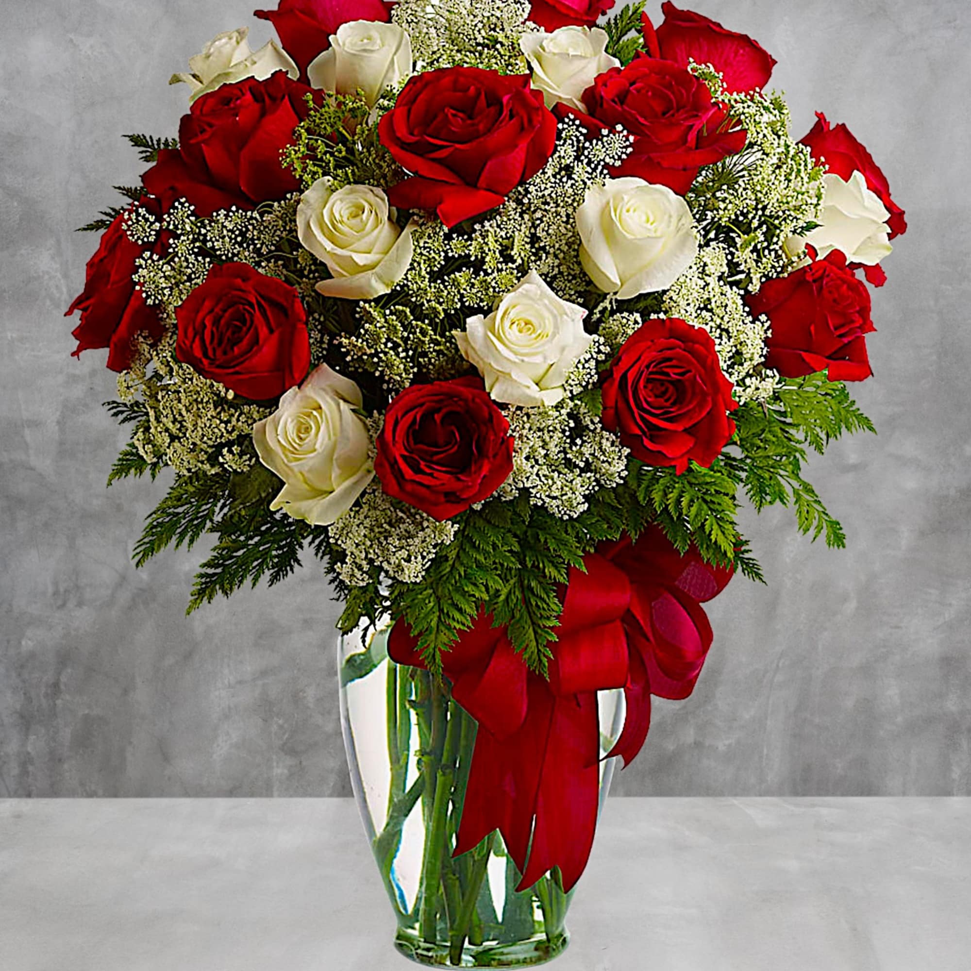 Red and white roses arranged in a clear glass vase with a red ribbon, photo 2 of 5