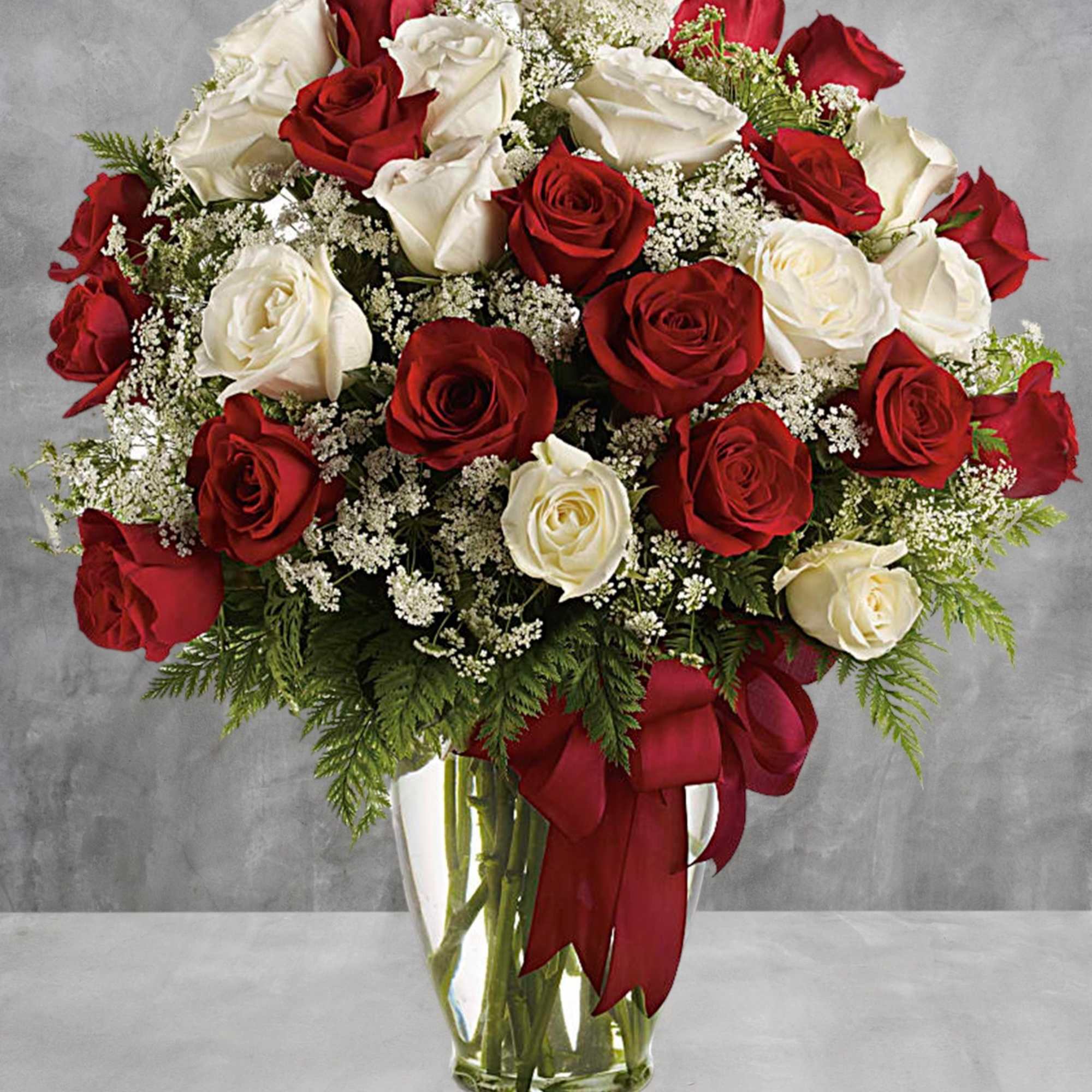 Red and white roses in a clear glass vase with a red ribbon, photo 2 of 5