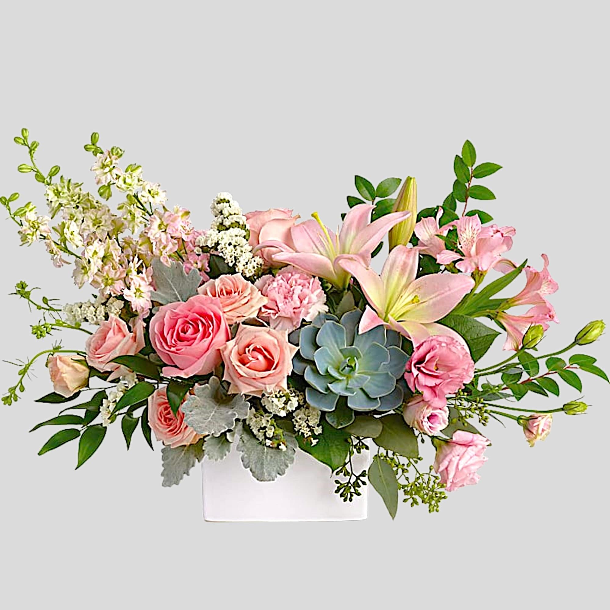 Pink roses and lilies in a white rectangular vase with succulents