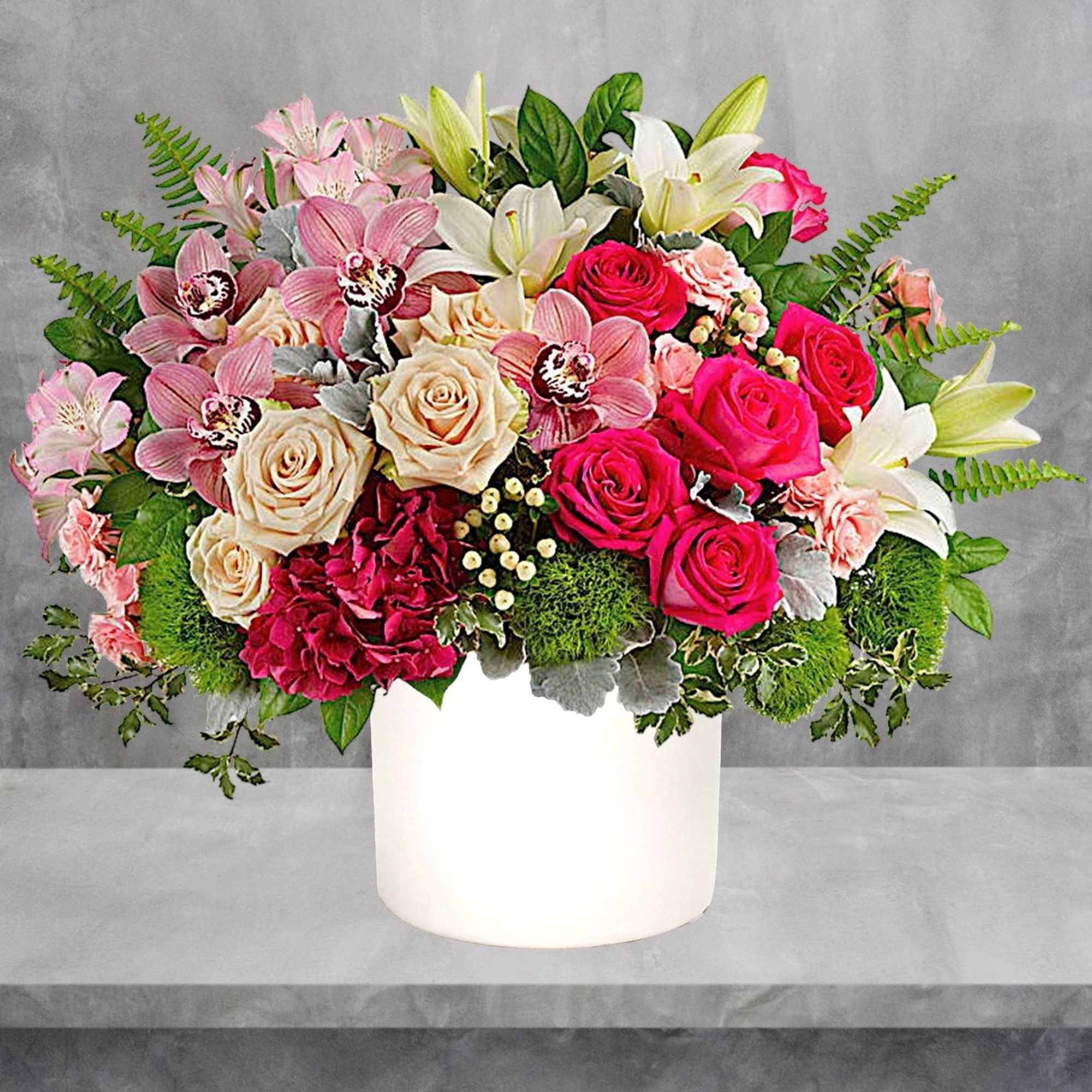 Mixed bouquet of roses, orchids, and lilies in a white vase