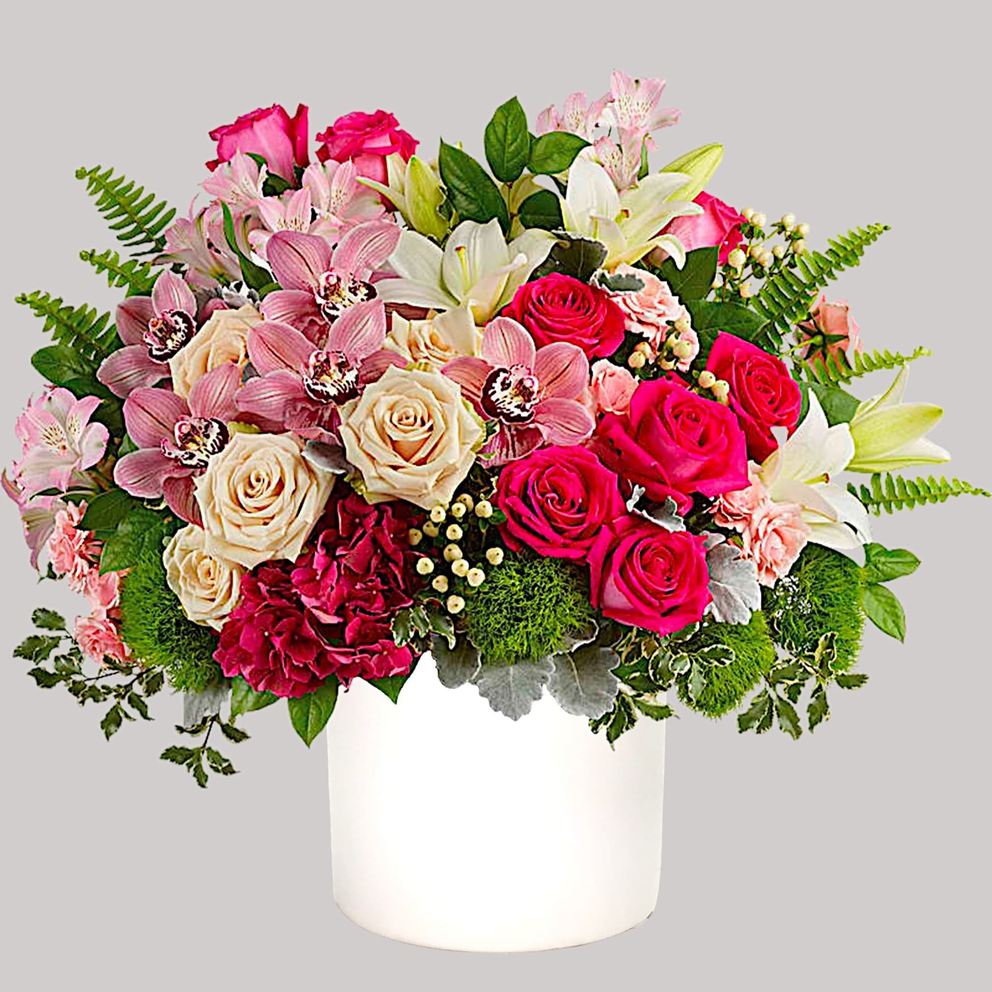 Mixed bouquet of pink roses, lilies, and orchids in a white vase