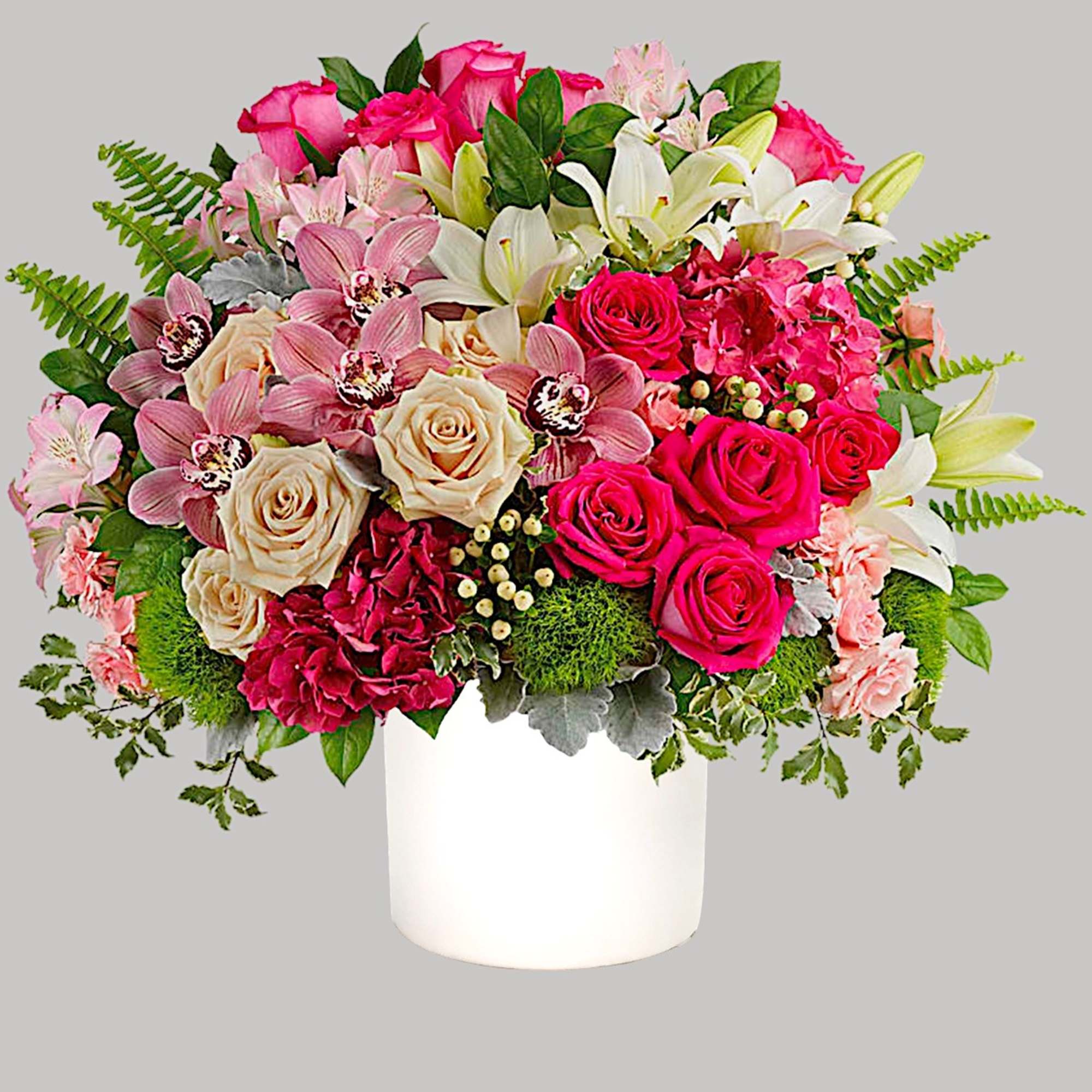 Bouquet of pink and white roses, lilies, and orchids in a white vase