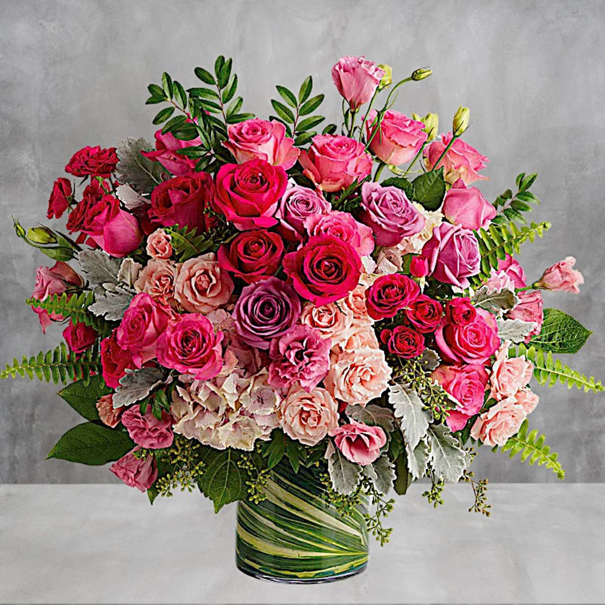 Large bouquet of pink and red roses in a striped glass vase