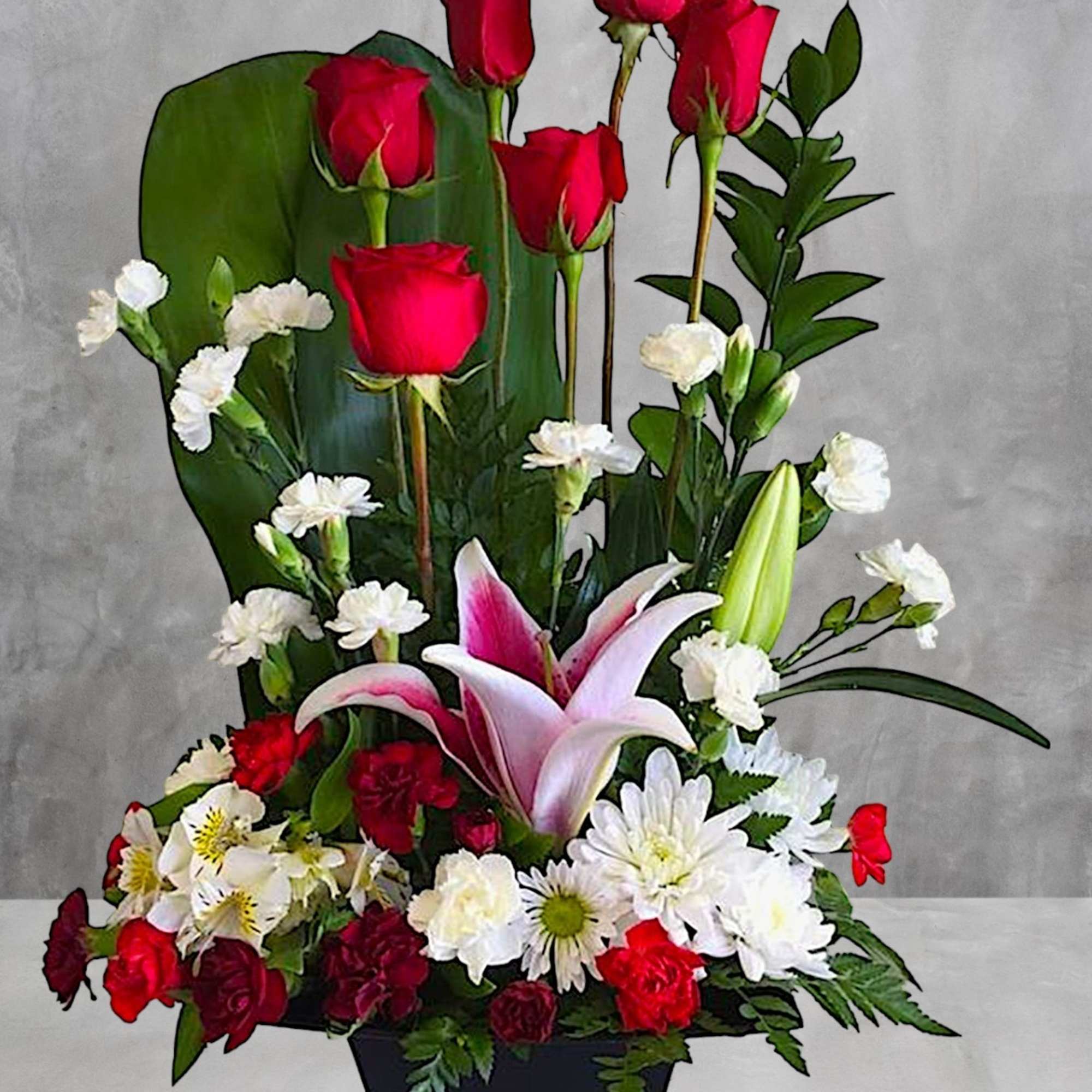 Tall floral arrangement with red roses, white daisies, and pink lilies in a black container