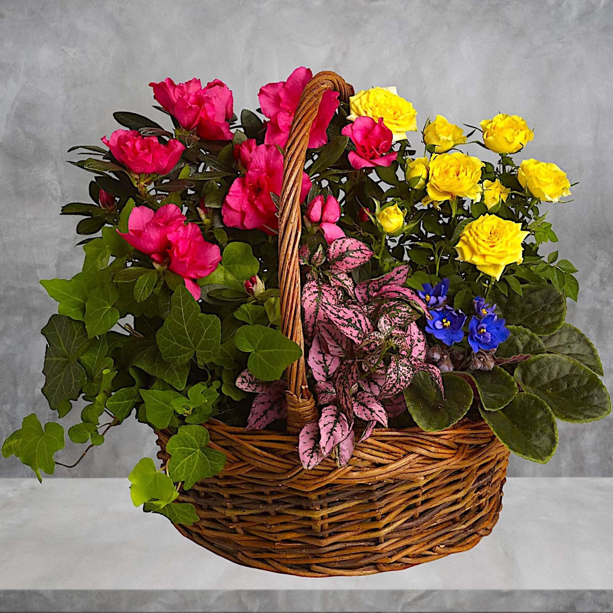 Basket of pink and yellow roses with mixed foliage and small blue flowers, photo 2 of 5