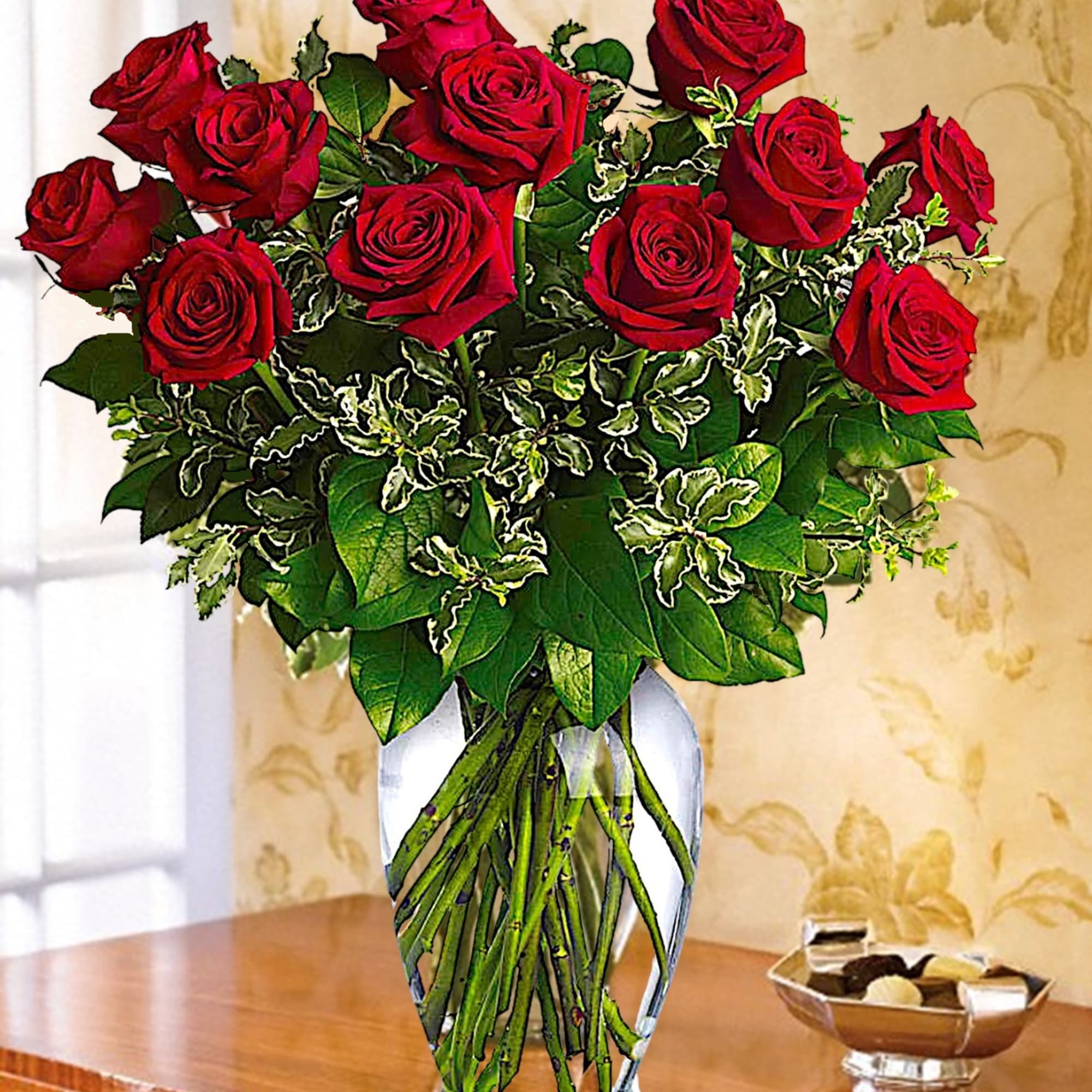 Red roses arranged in a clear glass vase with variegated greenery, photo 3 of 6