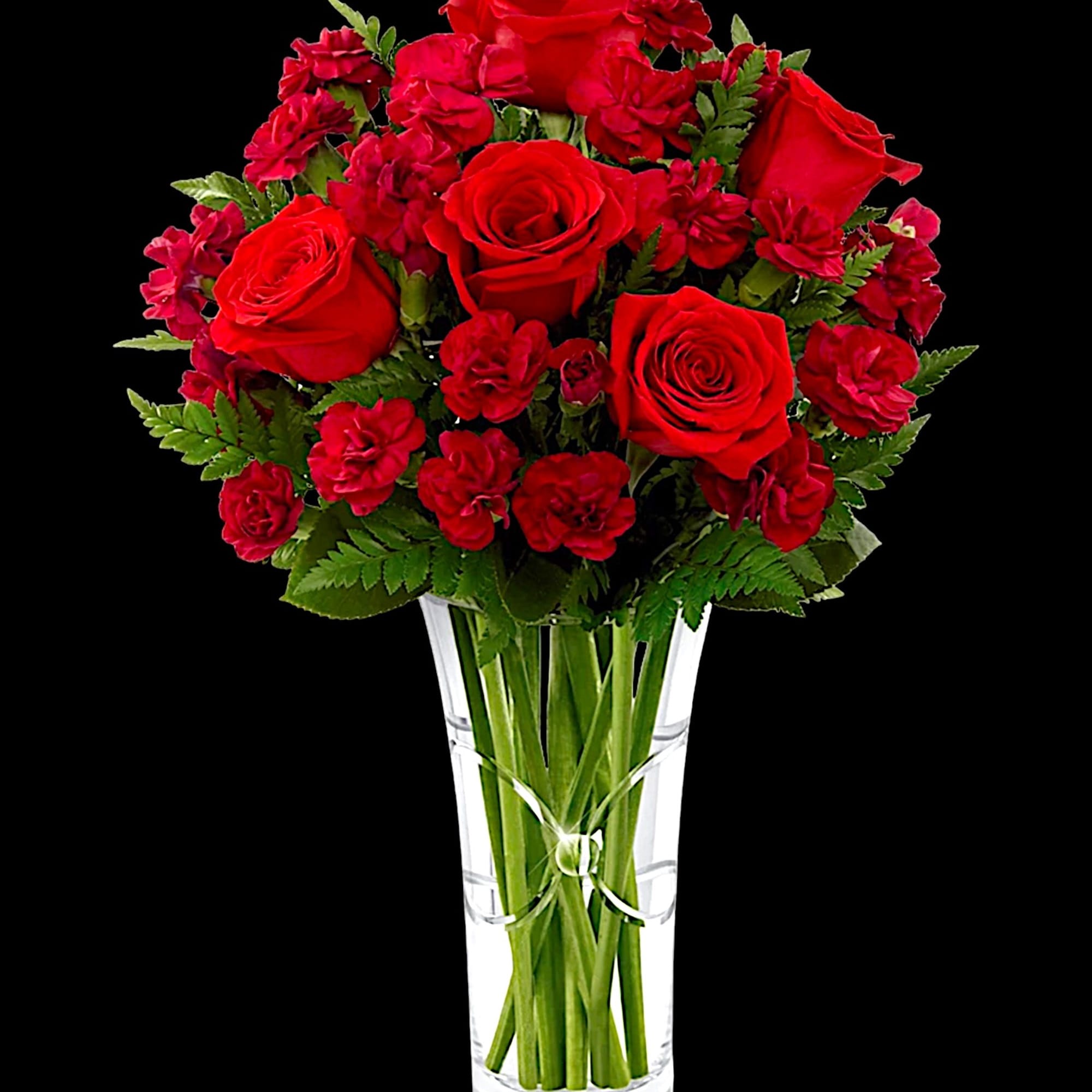 Red roses and carnations in a clear glass vase