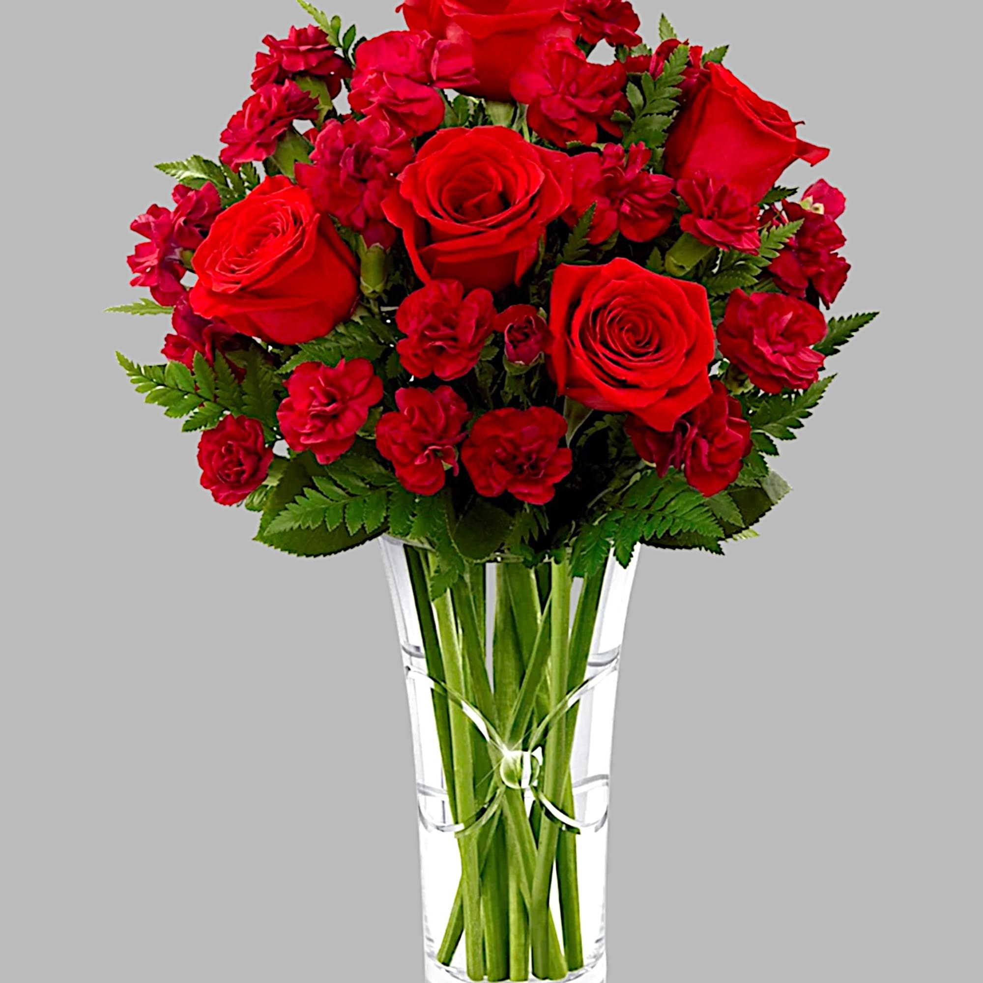 Red roses and carnations arranged in a clear glass vase, photo 5 of 5