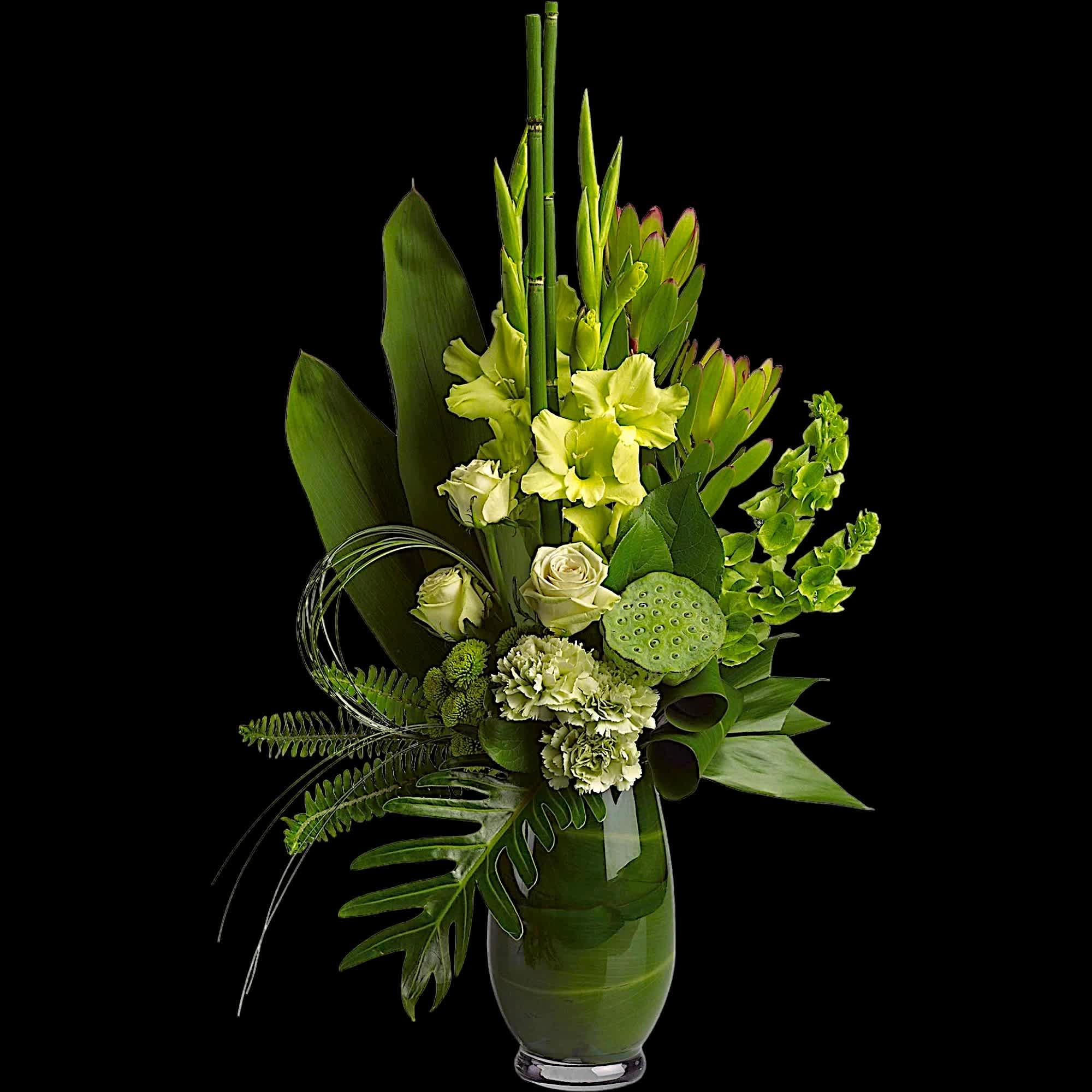 Green floral arrangement in a glass vase with pale blooms and tropical leaves