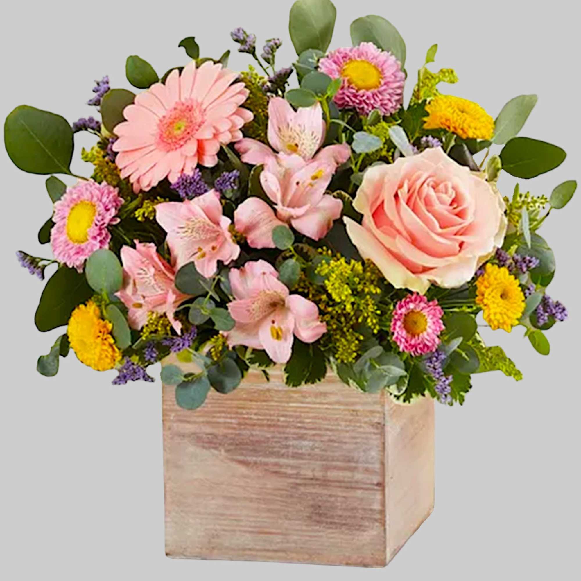 Mixed pink and yellow flowers in a wooden box vase