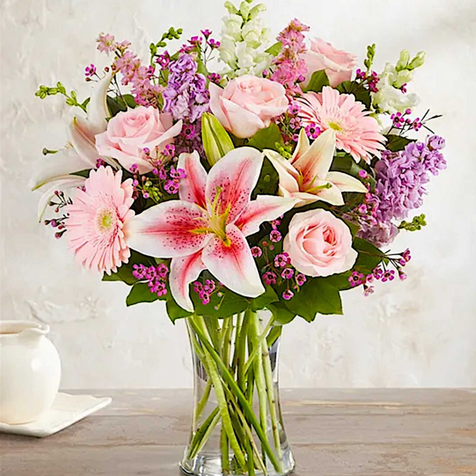 Pink roses and lilies arranged in a clear glass vase, photo 3 of 6