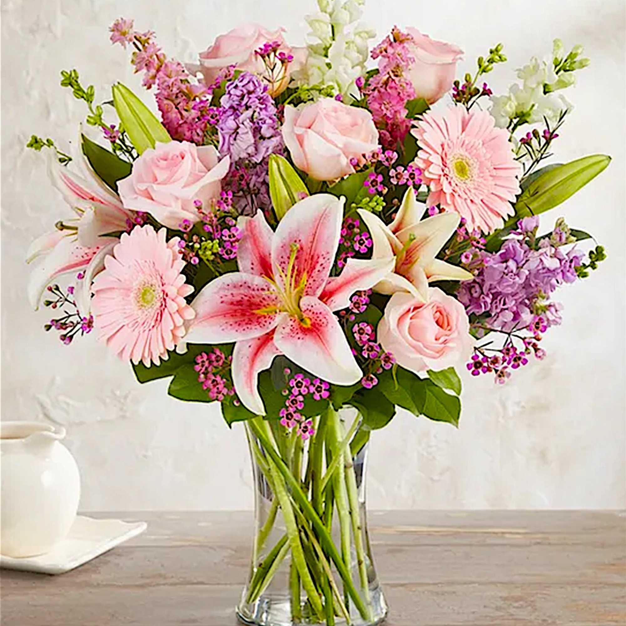 Pink roses and lilies with gerbera daisies in a clear glass vase