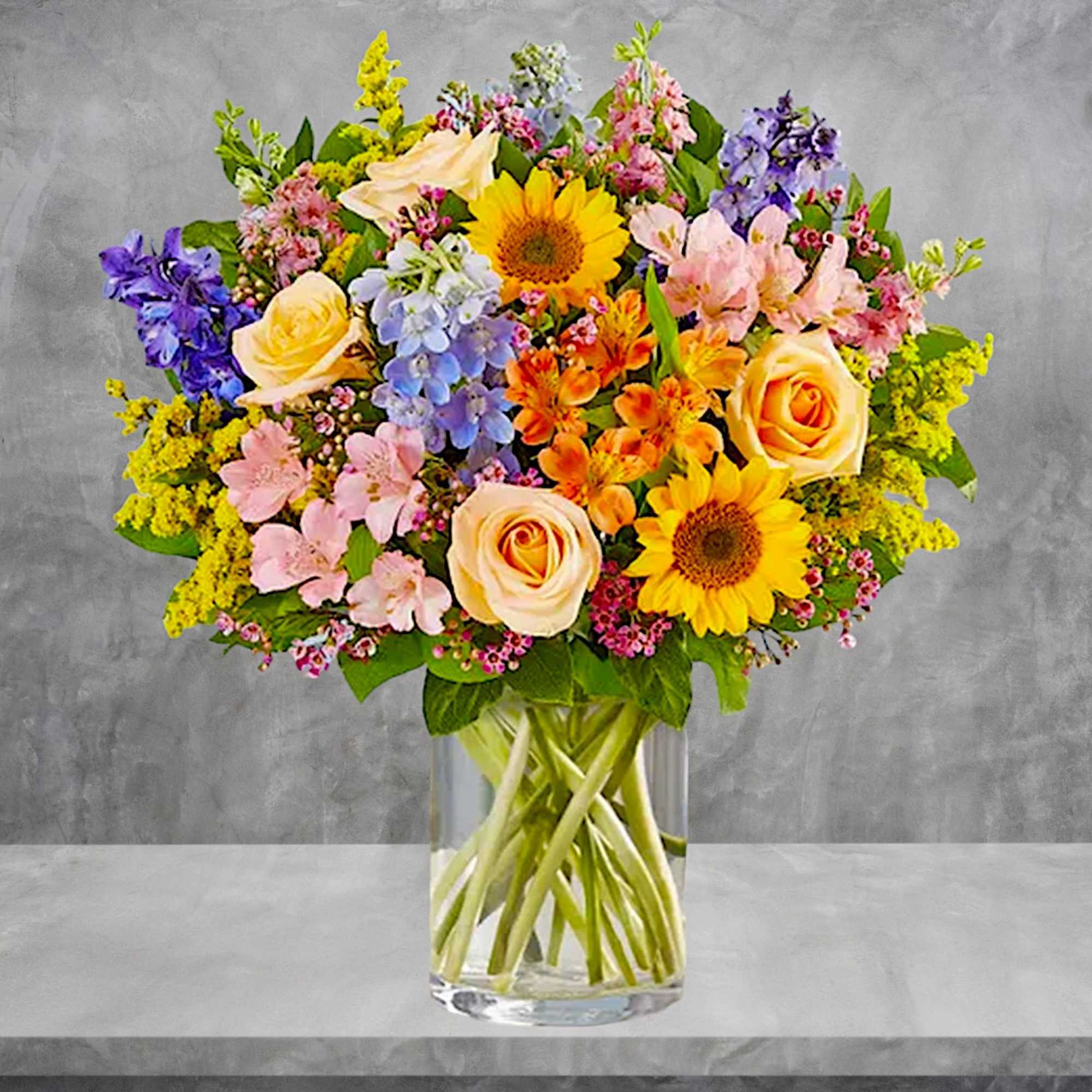 Mixed bouquet of roses, sunflowers, and pastel flowers in a glass vase, photo 4 of 6
