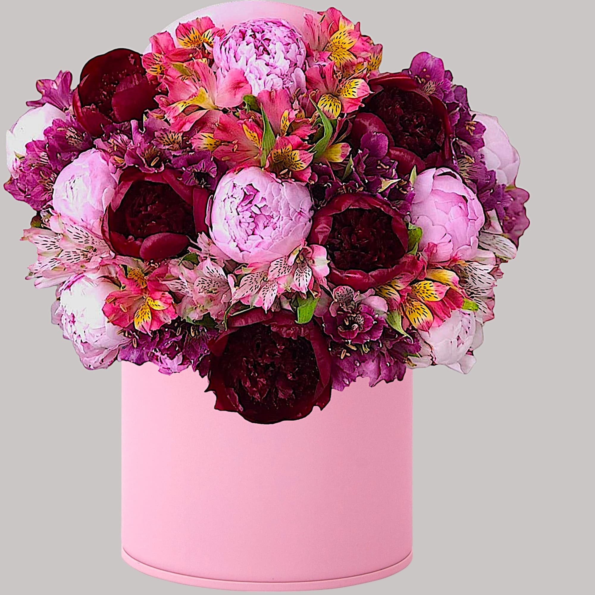 Pink and burgundy flower arrangement in a pink hatbox