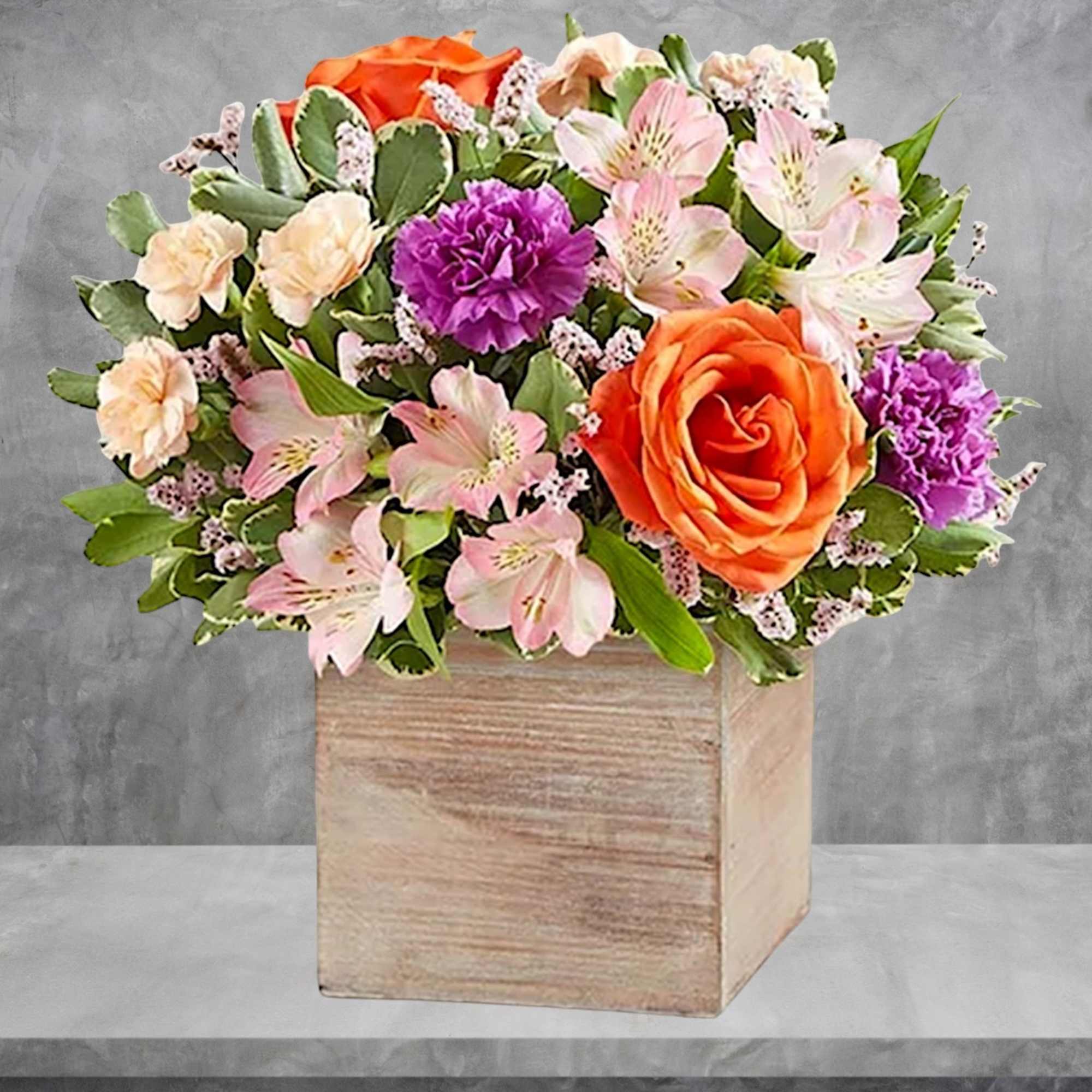 Mixed bouquet in a wooden cube vase with orange and pink flowers