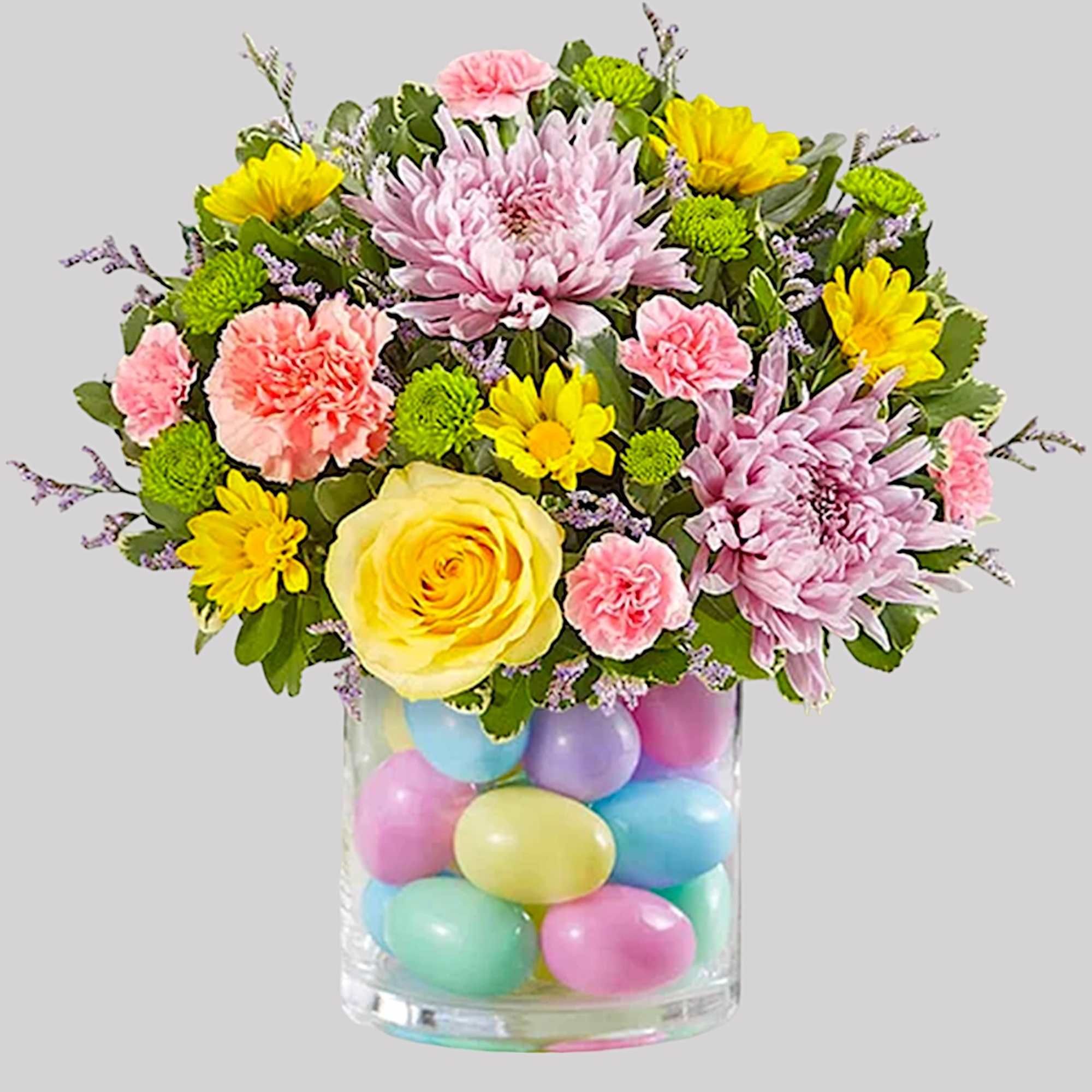 Mixed pastel bouquet in a clear vase filled with colorful eggs