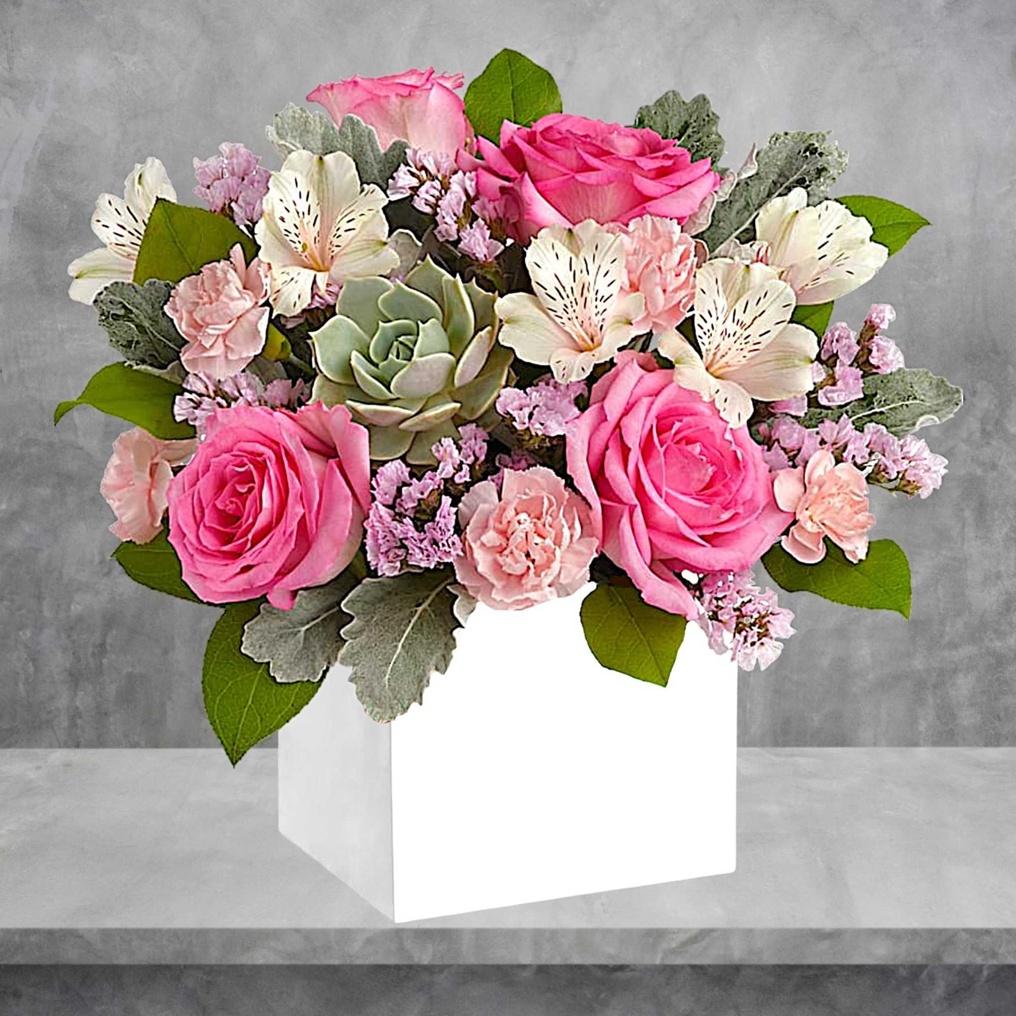 Pink roses and pale flowers arranged in a white box vase