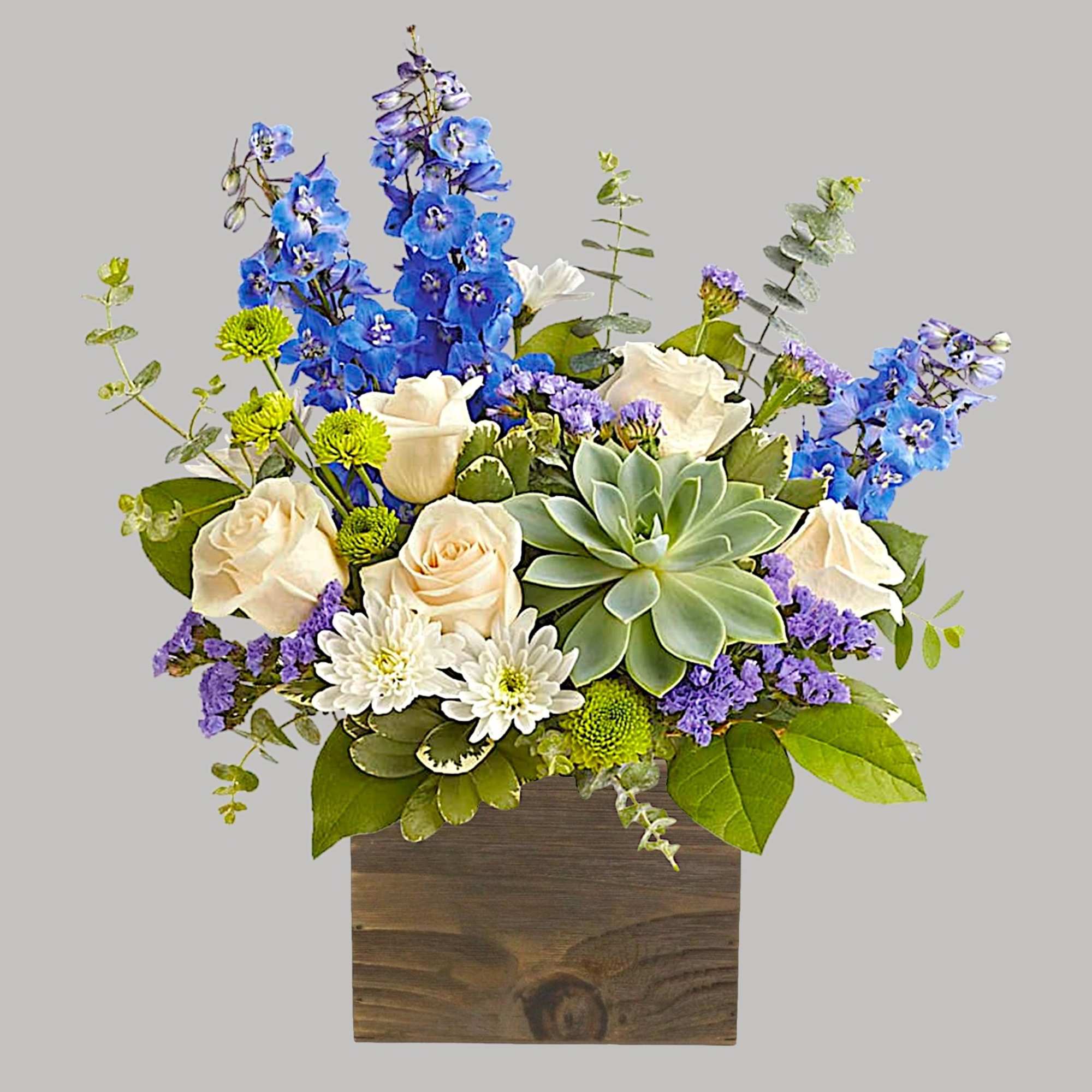 Mixed bouquet with blue delphinium, cream roses, and a succulent in a wooden box