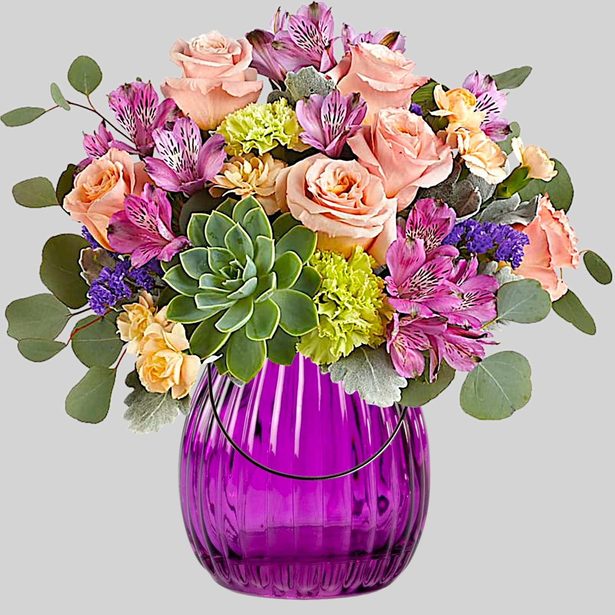 Mixed bouquet of pink roses, purple alstroemeria, and succulents in a purple glass vase