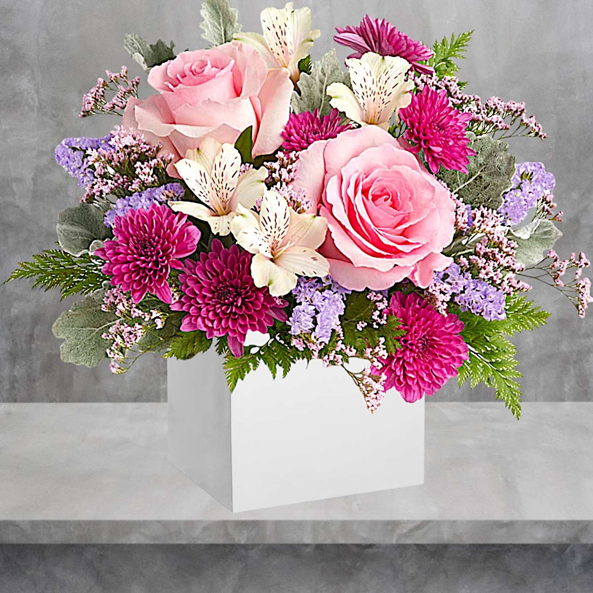 Pink roses and magenta mums in a white box with purple filler flowers