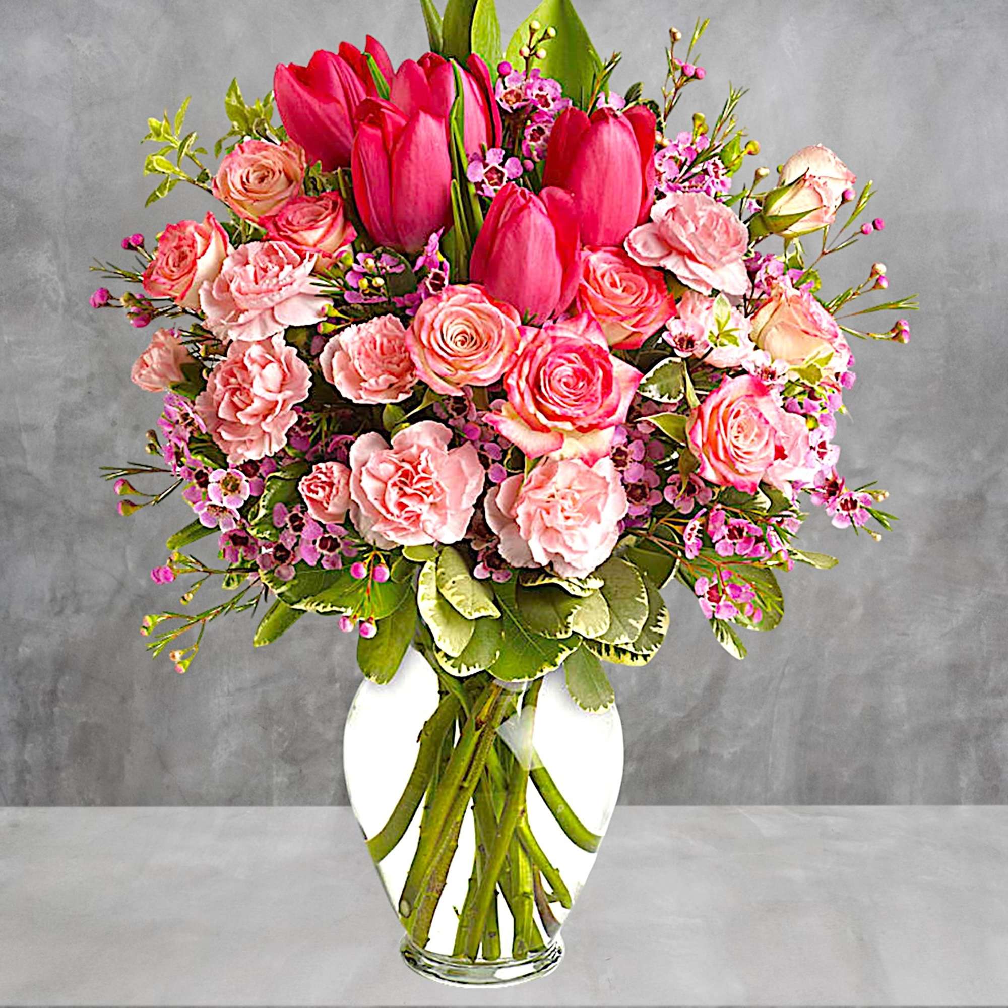 Pink tulips and roses arranged in a white vase