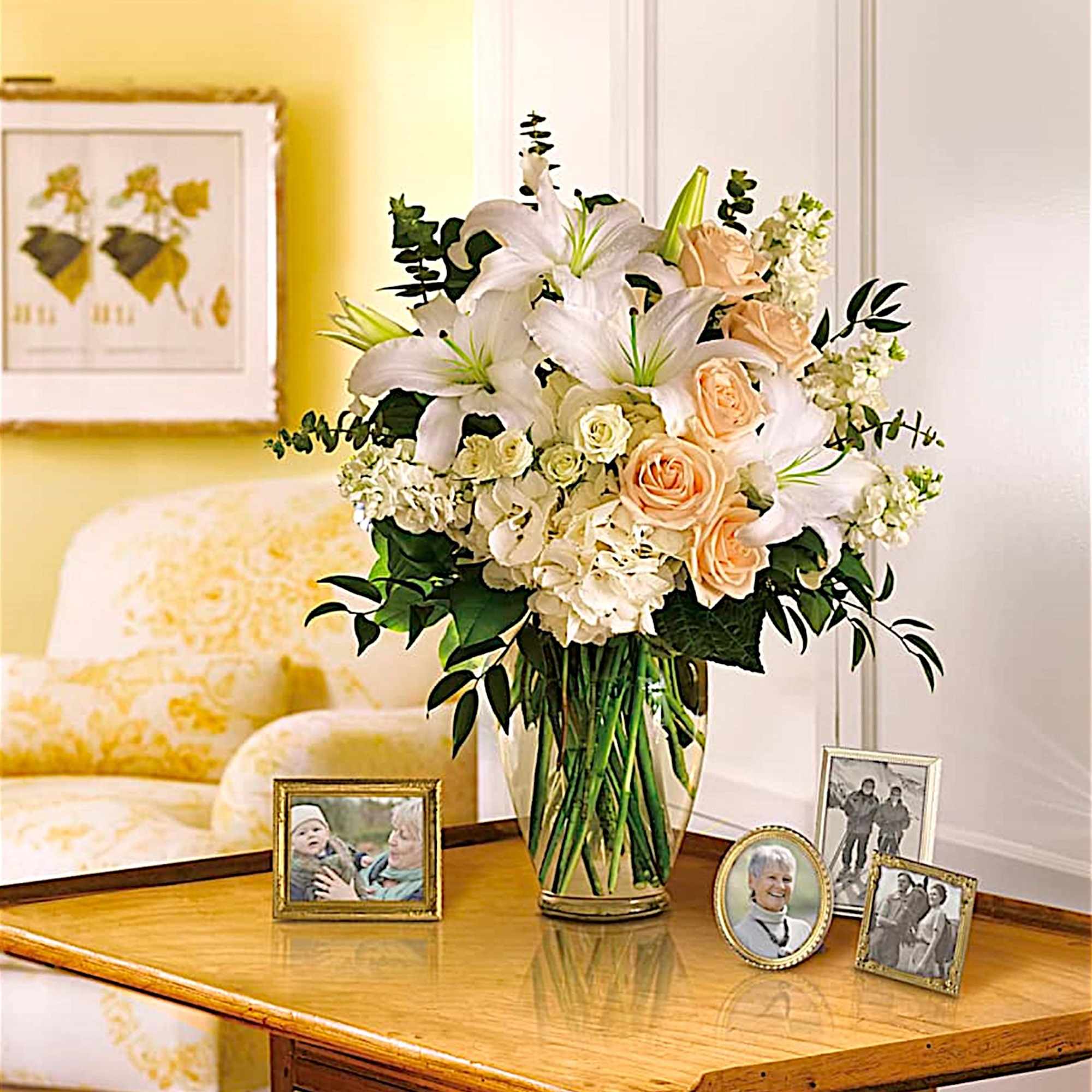 White lilies and peach roses in a glass vase on a table