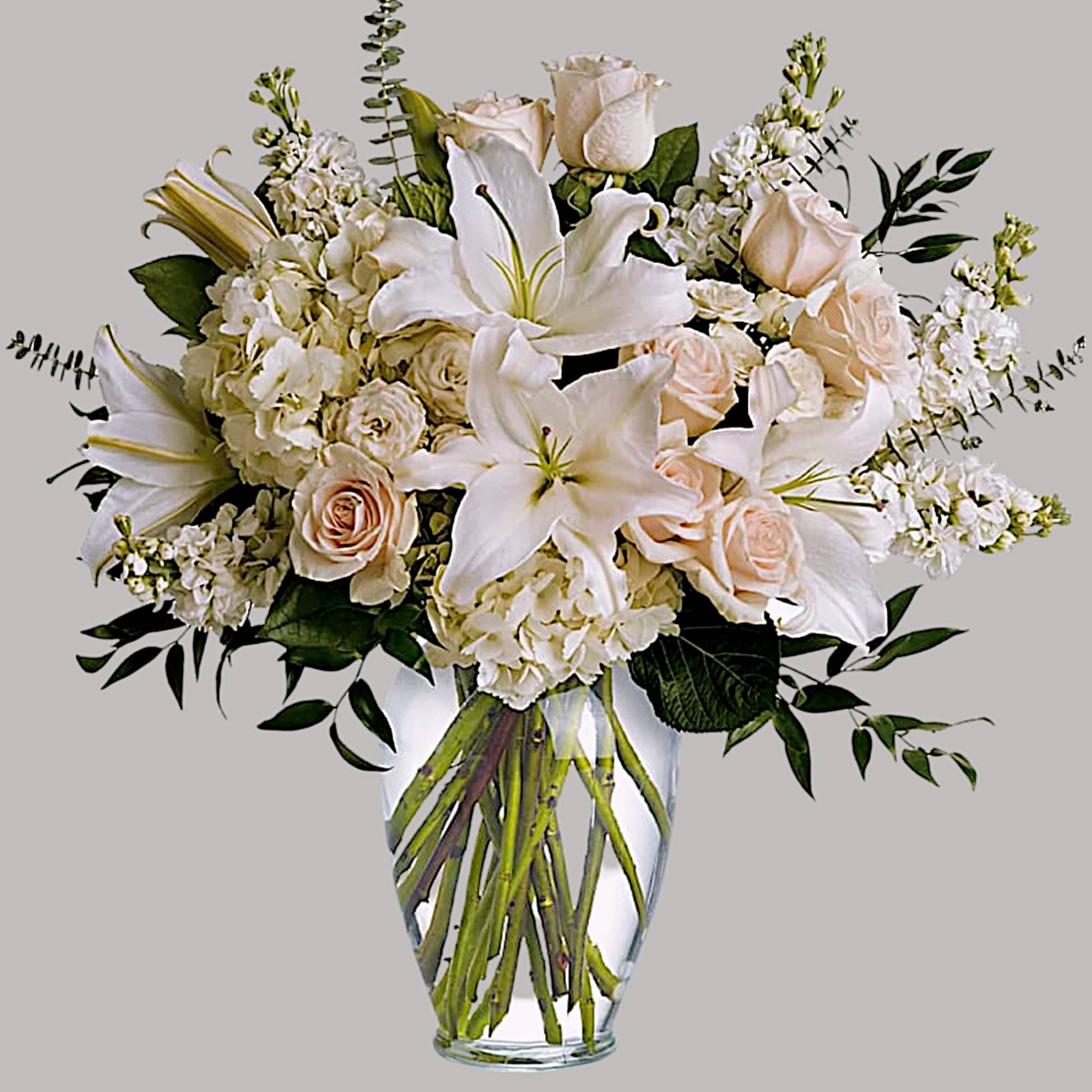 White lilies and pale roses in a clear glass vase, photo 5 of 5