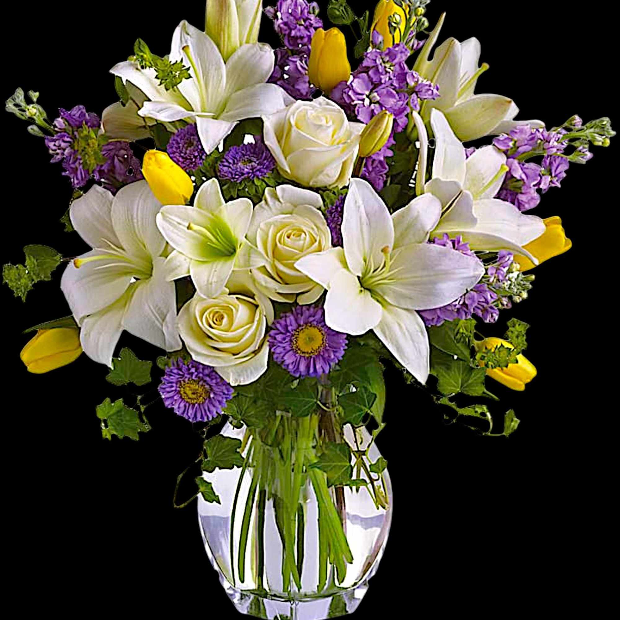 White lilies, roses, and purple flowers in a clear glass vase