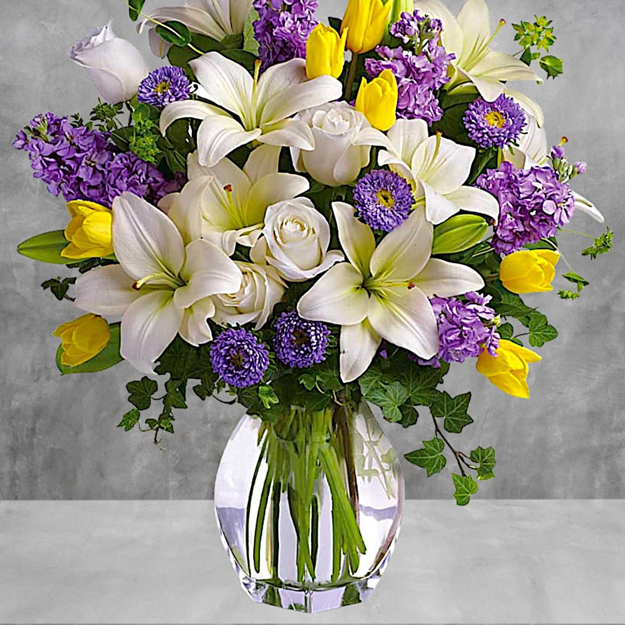 Bouquet of white lilies, purple flowers, and yellow tulips in a glass vase, photo 3 of 5