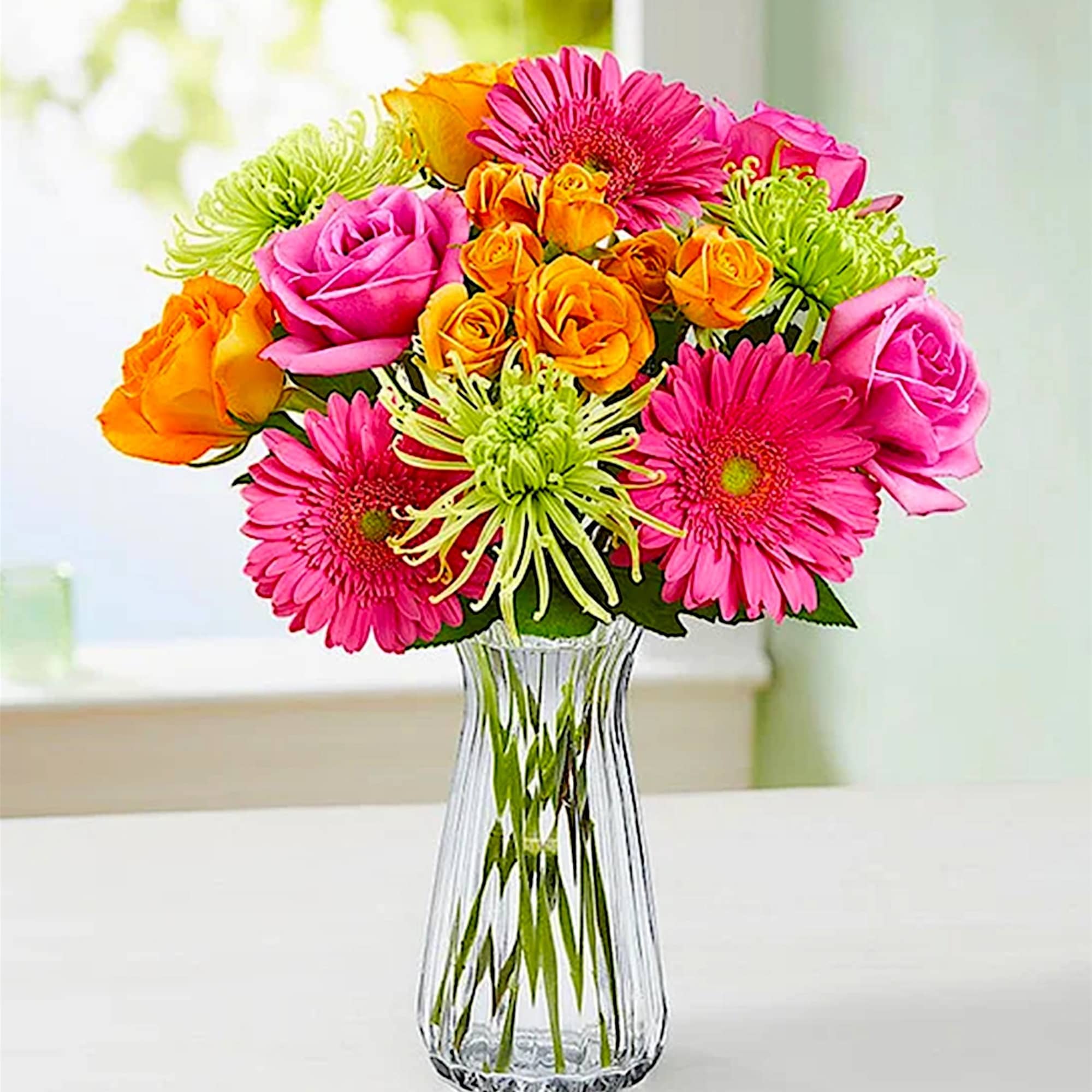 Bright mixed bouquet of pink and orange flowers in a clear glass vase, photo 2 of 5