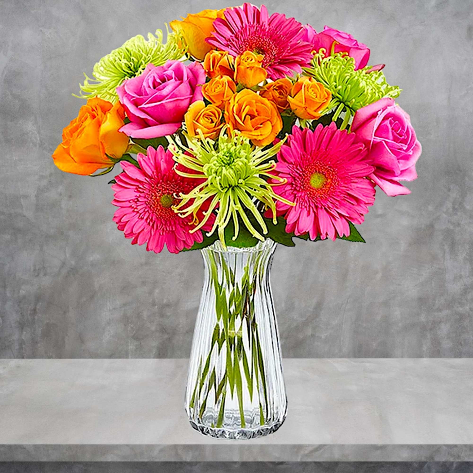 Bright mixed bouquet of pink, orange, and green flowers in a clear glass vase