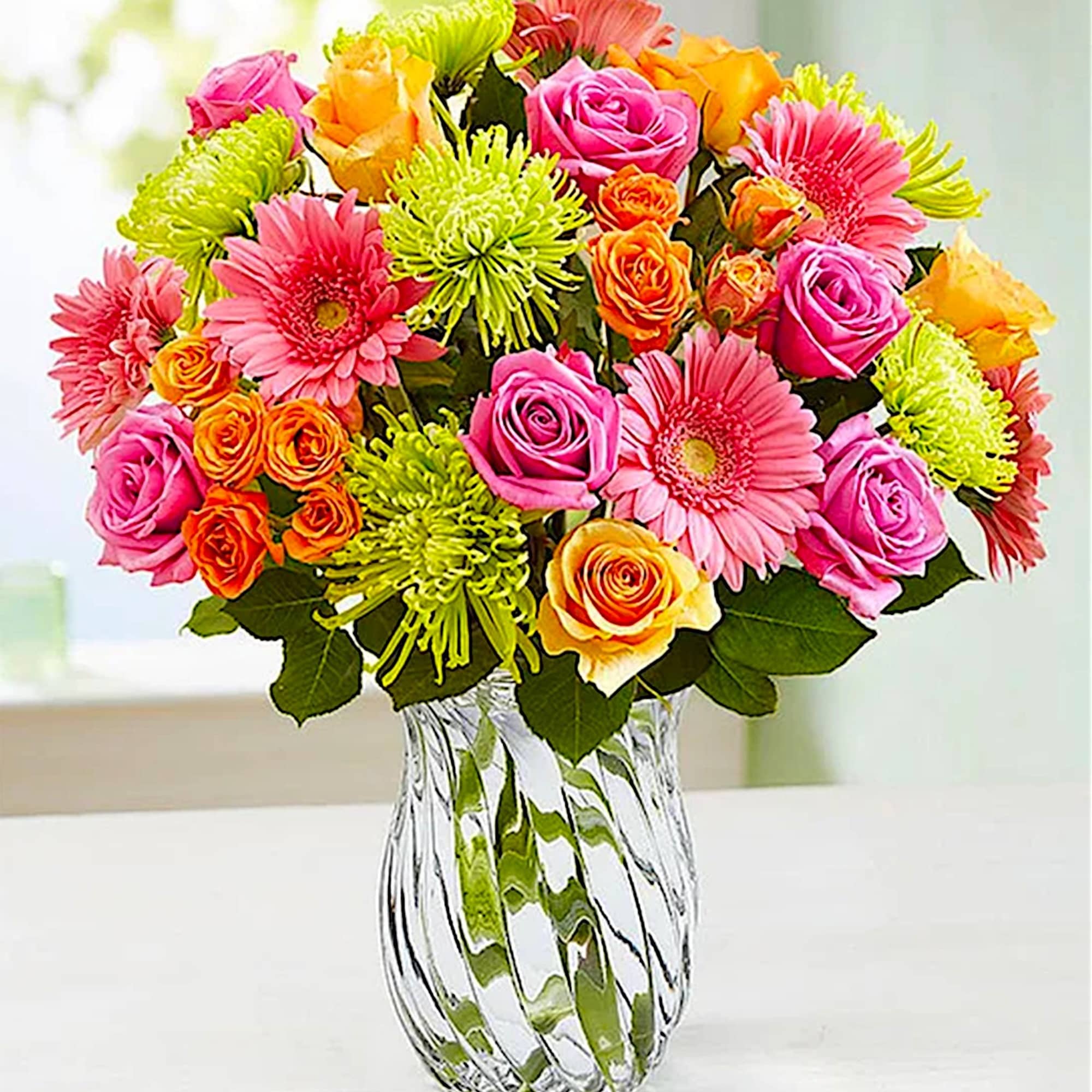 Bright mixed bouquet of roses and gerbera daisies in a clear glass vase