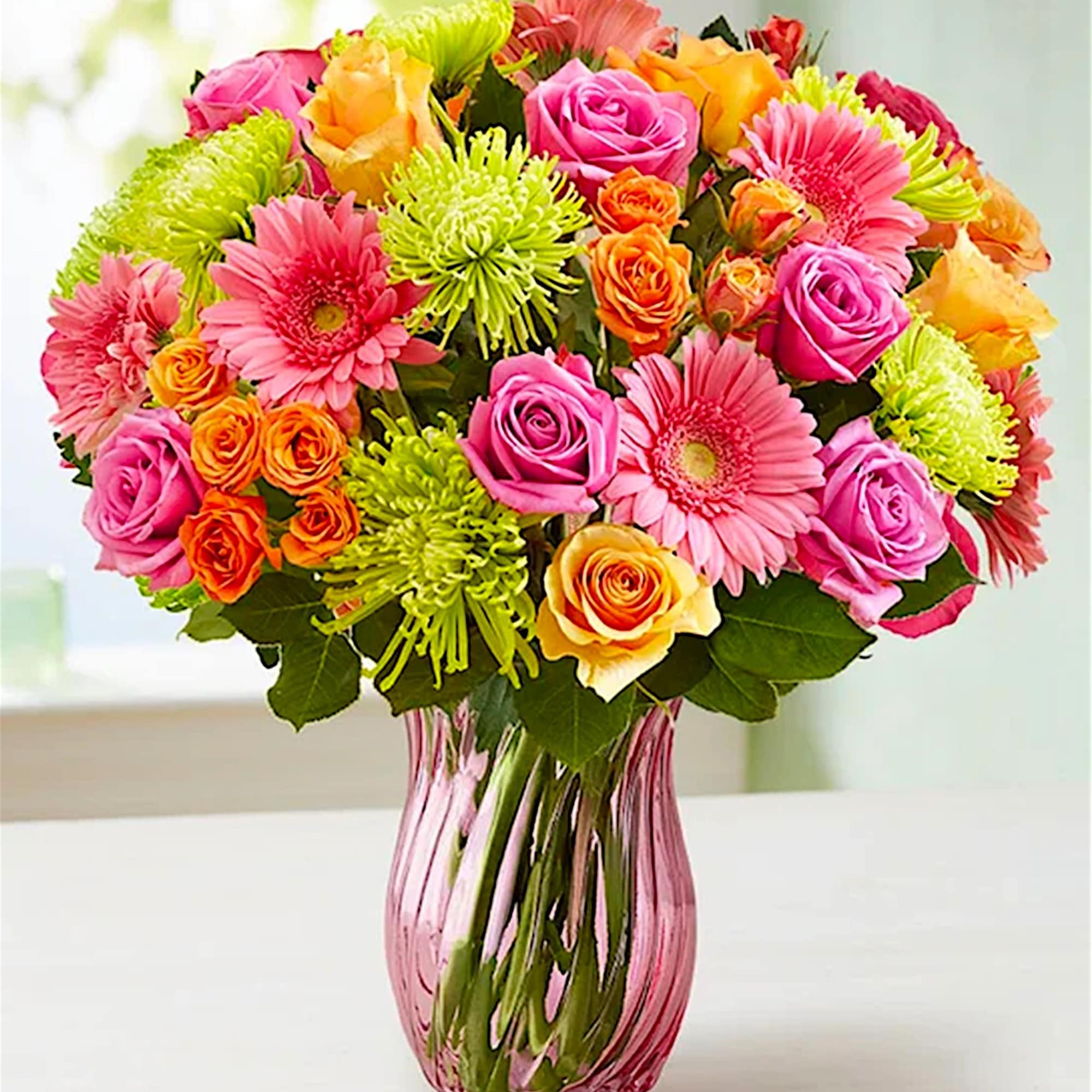 Bouquet of pink, orange, and yellow flowers in a pink glass vase