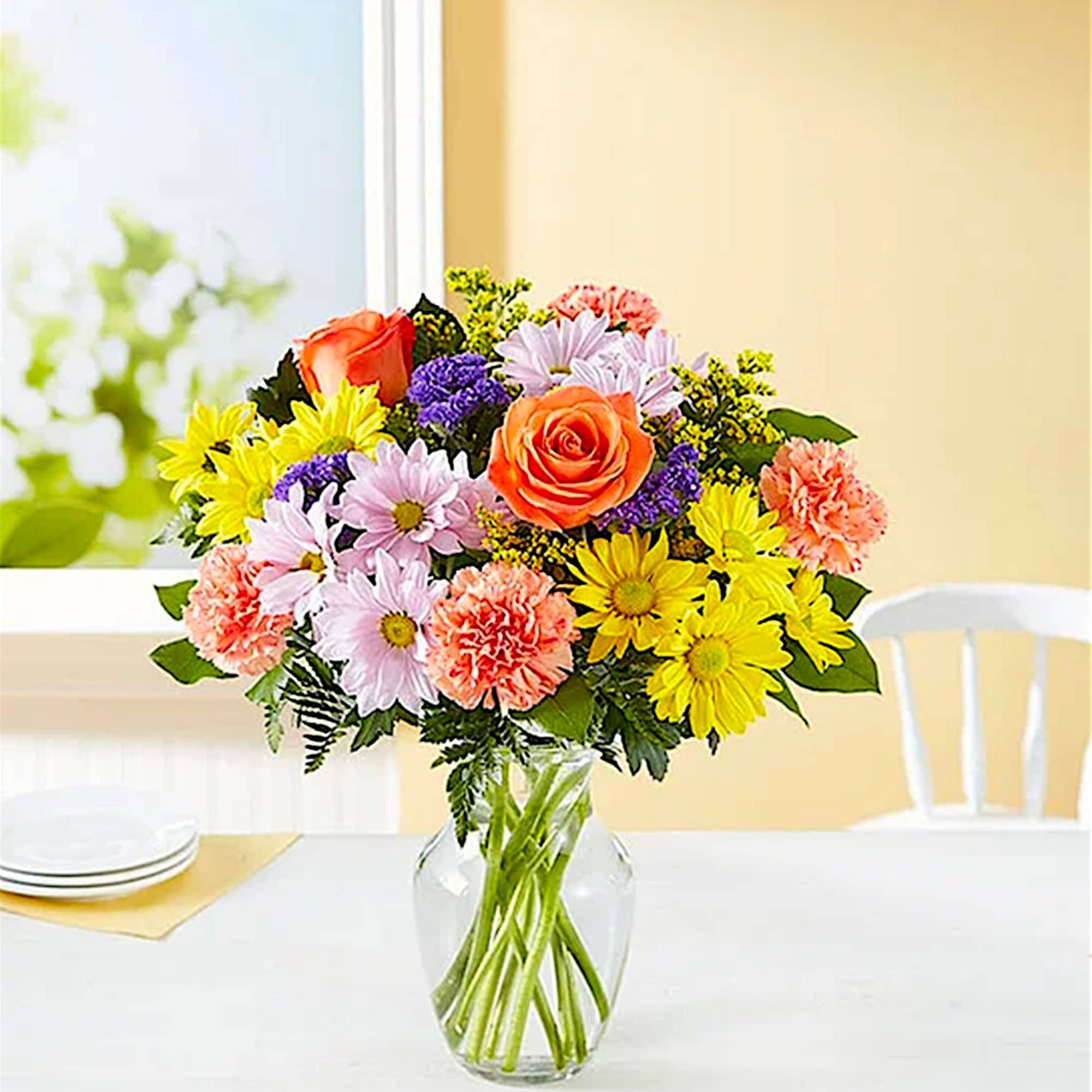 Colorful bouquet of roses, daisies, and carnations in a clear glass vase
