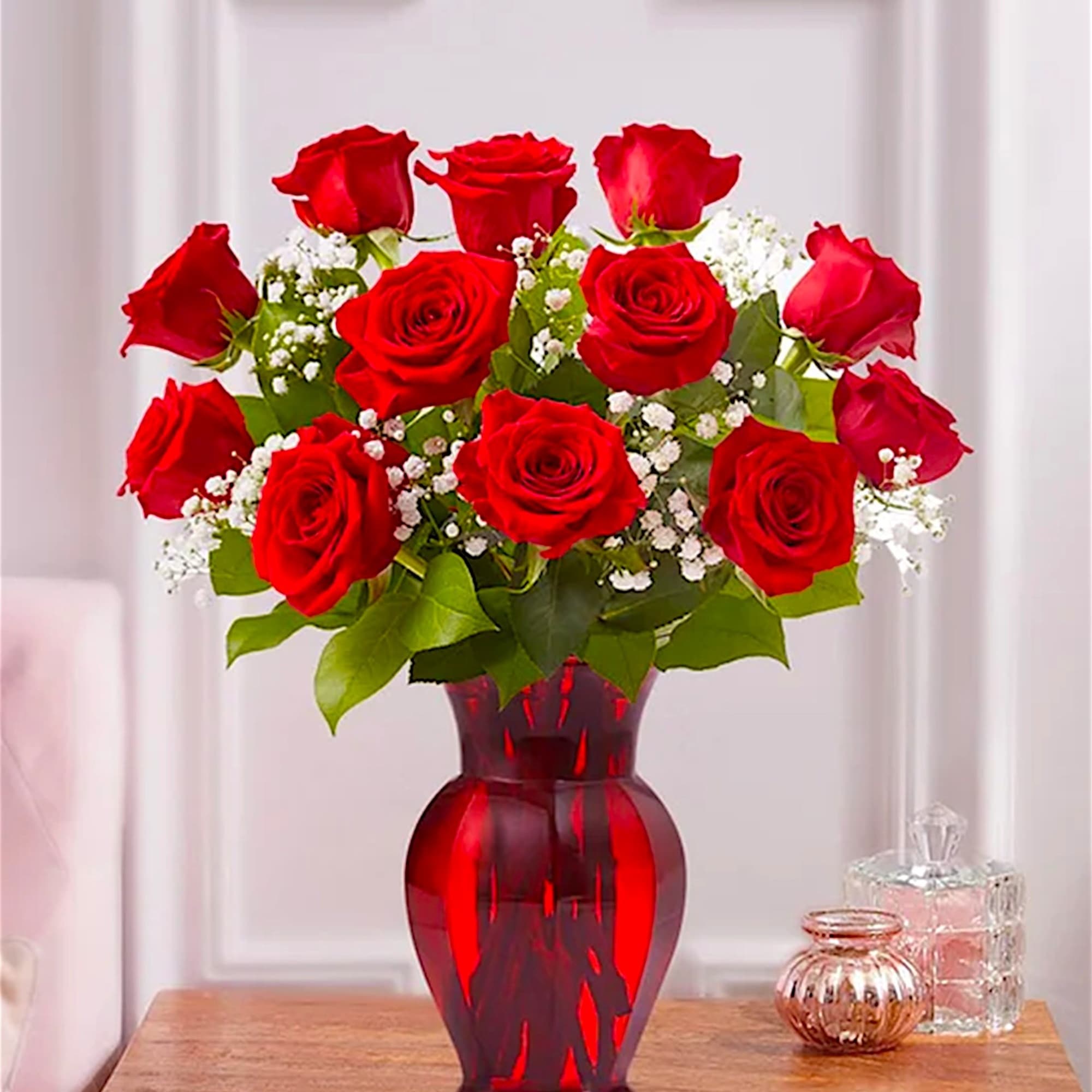 Red roses arranged in a red glass vase with white filler flowers, photo 2 of 5
