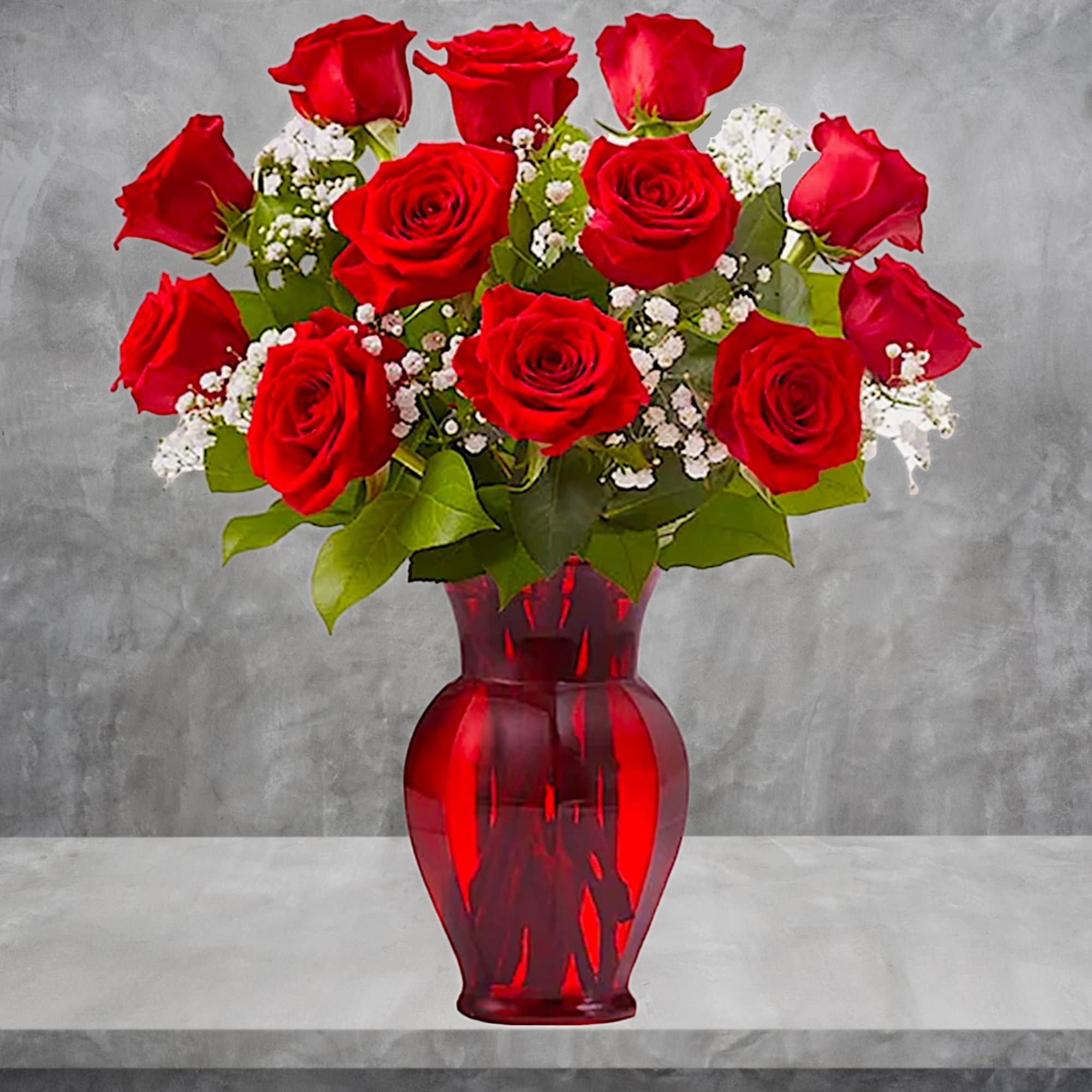 Red roses arranged in a red glass vase with white filler flowers, photo 3 of 5
