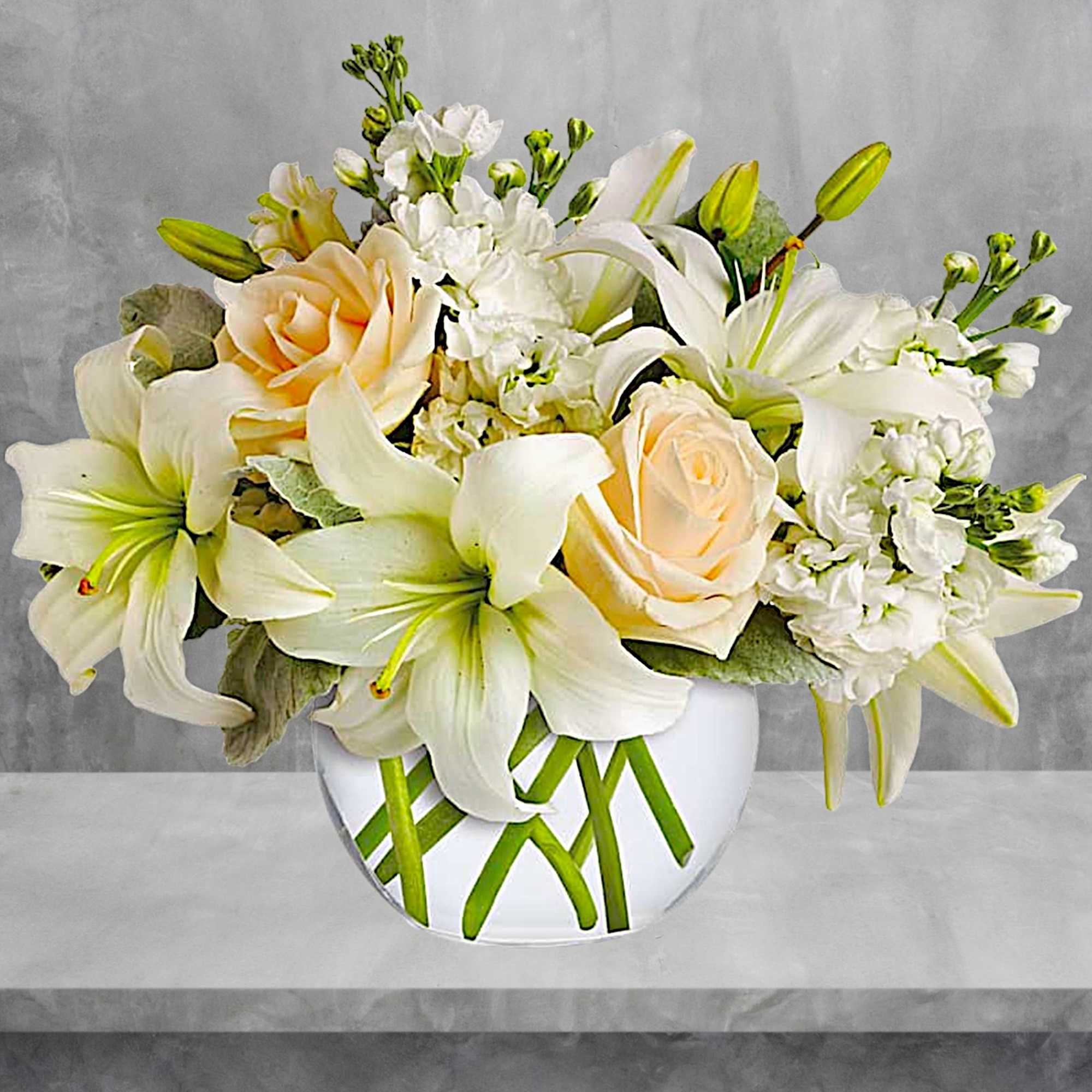 White lilies and peach roses arranged in a clear glass vase